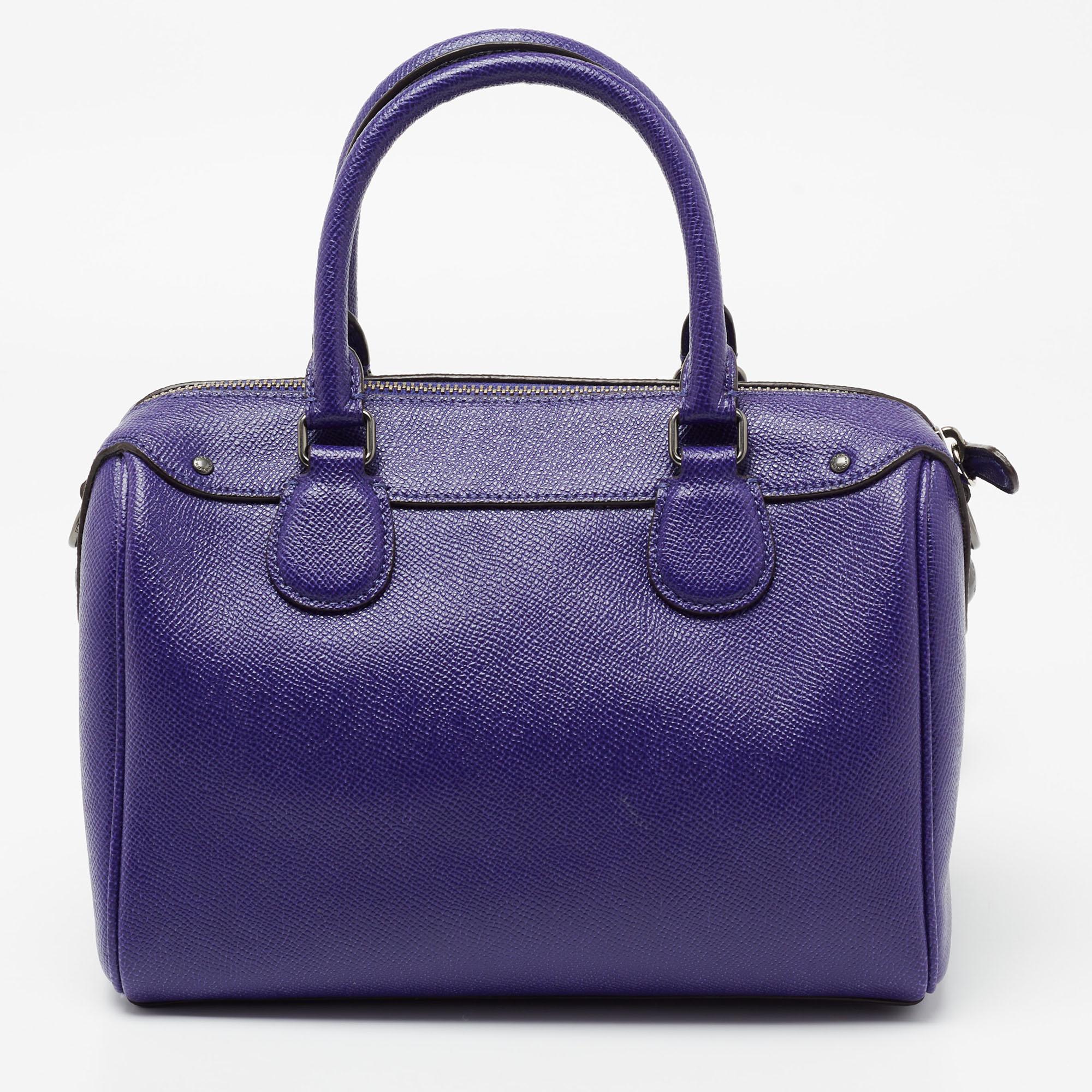 To make you always be in style whenever you step out, Coach offers you this stunner of a bag. Crafted from purple-hued leather, the bag features dual handles, a removable shoulder strap, and a brand leather tag. The top zip closure opens to a