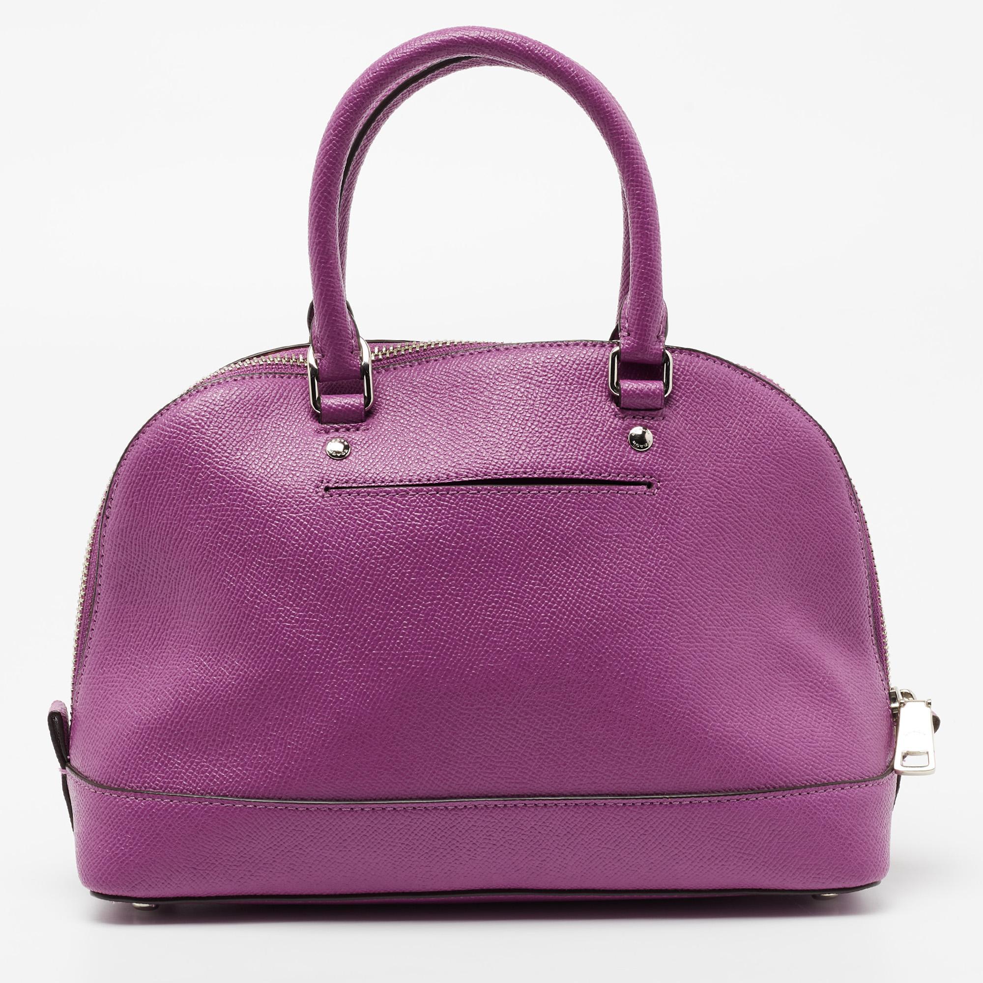 The Sierra is one of the most loved bags from Coach. This mini Sierra satchel is crafted in purple leather and equipped with a fabric interior, two handles, a shoulder strap, and metal feet. It is complete with the brand name on the