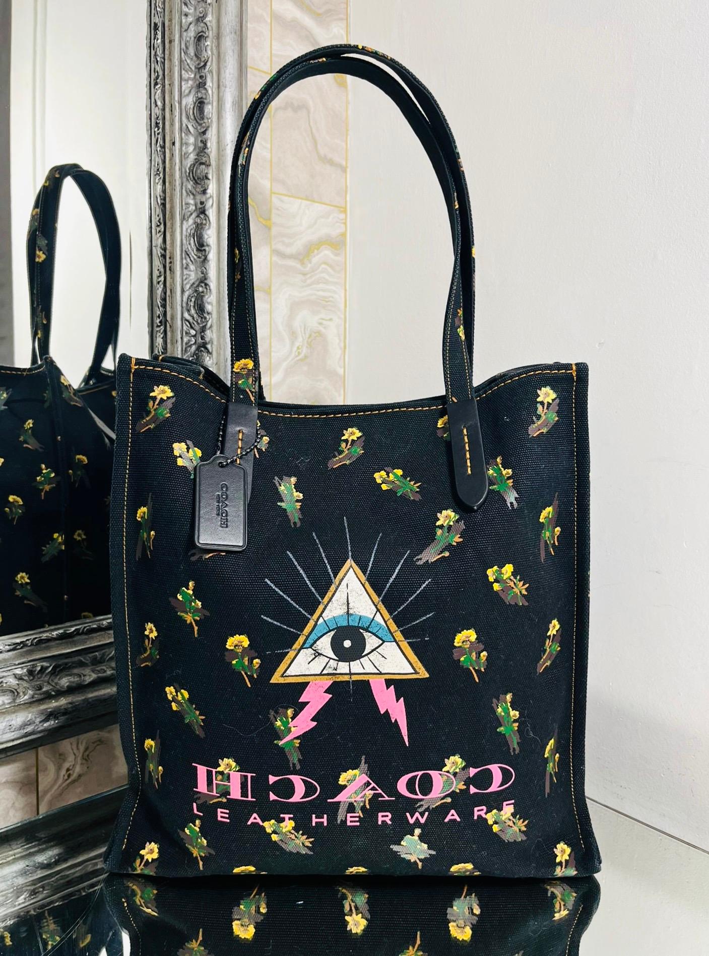 Coach Pyramid Eye Canvas Tote Bag

Black bag designed with a mixed print of florals and the Pyramid Eye symbol.

Detailed with pink, reversed lettering form the Coach logo at the front.

Featuring dual top handle and leather accents with removable