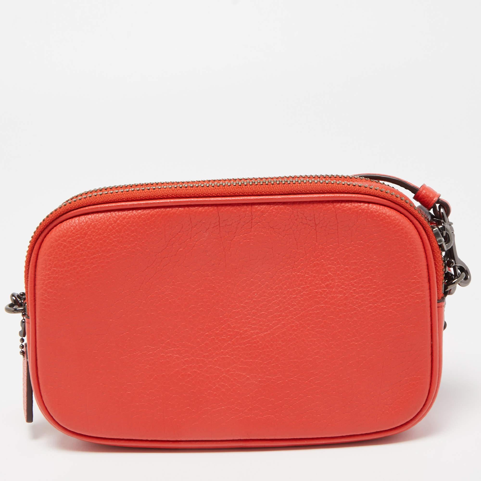 The Coach crossbody clutch is a stylish and compact accessory. Crafted from rich red coral leather, it features intricate embroidery, adding a touch of elegance. With a detachable crossbody strap, it offers versatility and convenience for any
