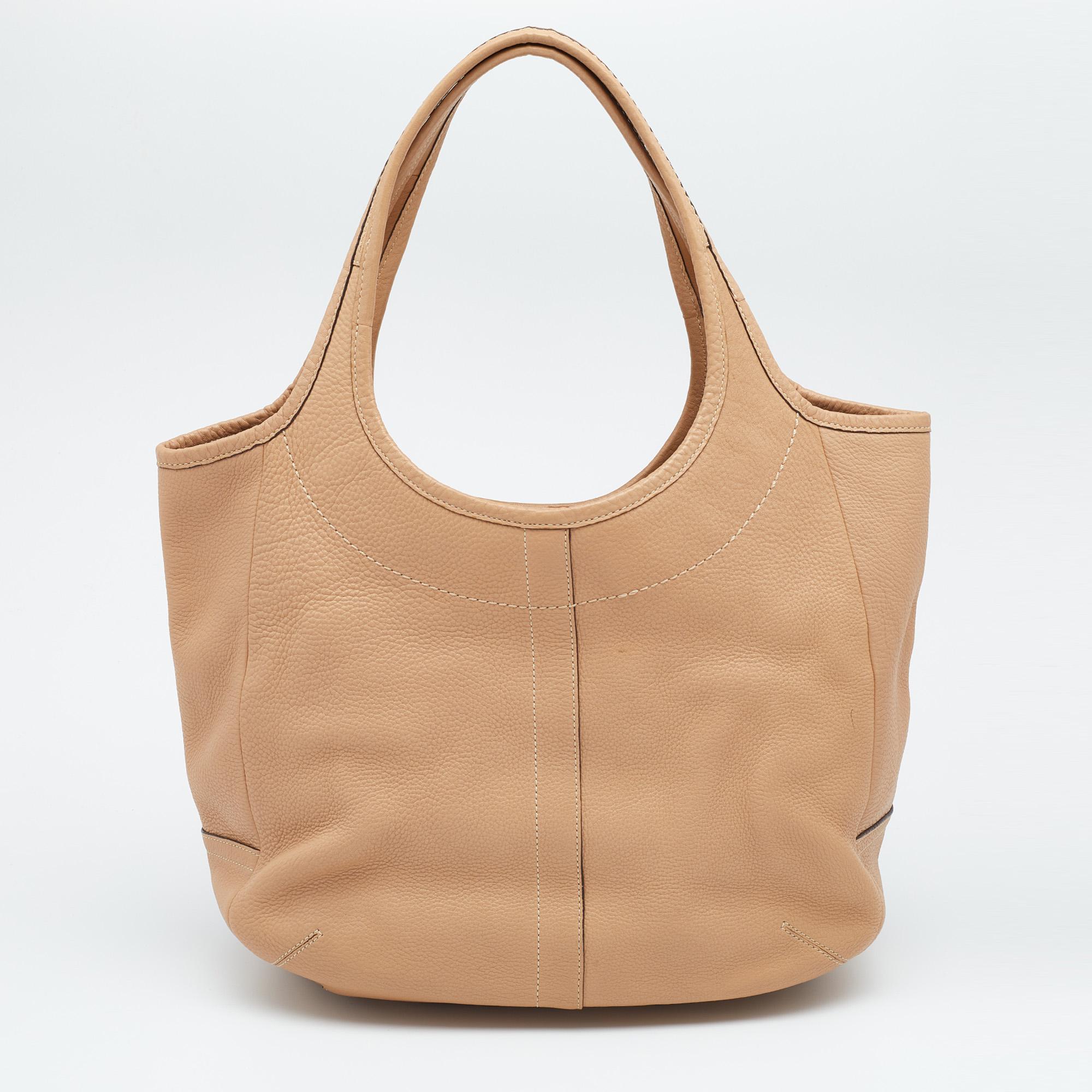 Flaunt your unique aesthetics in fashion with this fabulous XL Ergo Legacy tote from Coach. It is made from tan pebbled leather on the exterior. It features gold-toned hardware and a satin-lined interior. The structured silhouette of this tote is
