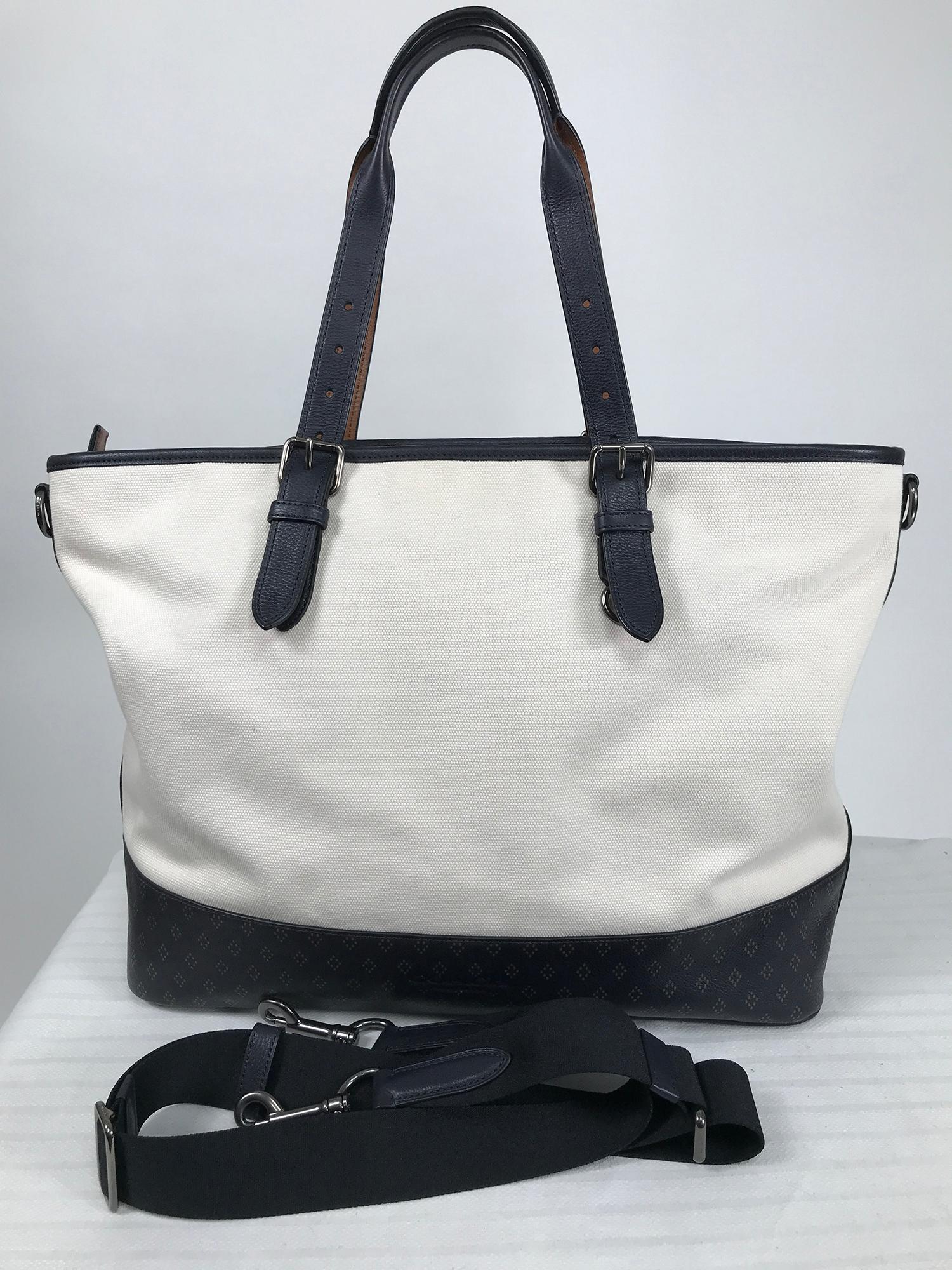 Coach white canvas with black leather trim, the deep base is black and tan diamond print. Double handles, rolled leather top with adjustable buckles. Gunmetal hardware. Zipper top closure. Adjustable removable shoulder strap. Interior is lined in