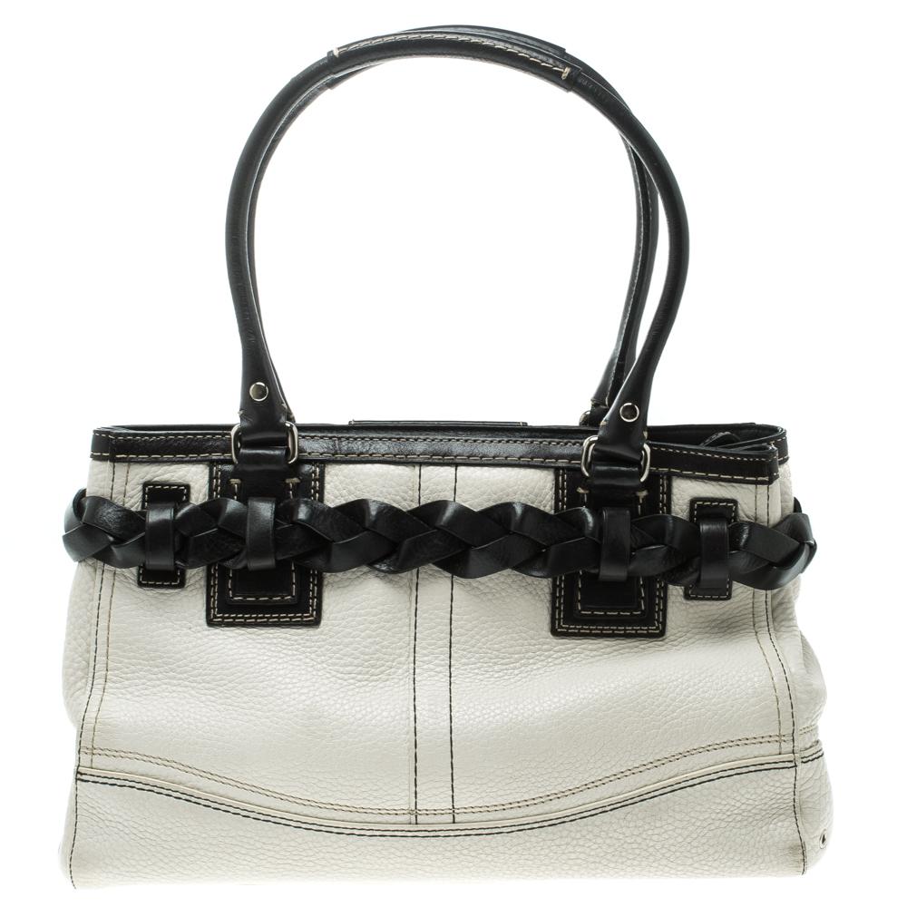 This fashionable Coach bag will make a standout addition to your collection. Crafted from leather the bag comes with dual handles and protective metal feet at the bottom. The bag features a braided belt that wraps around the exterior and has a