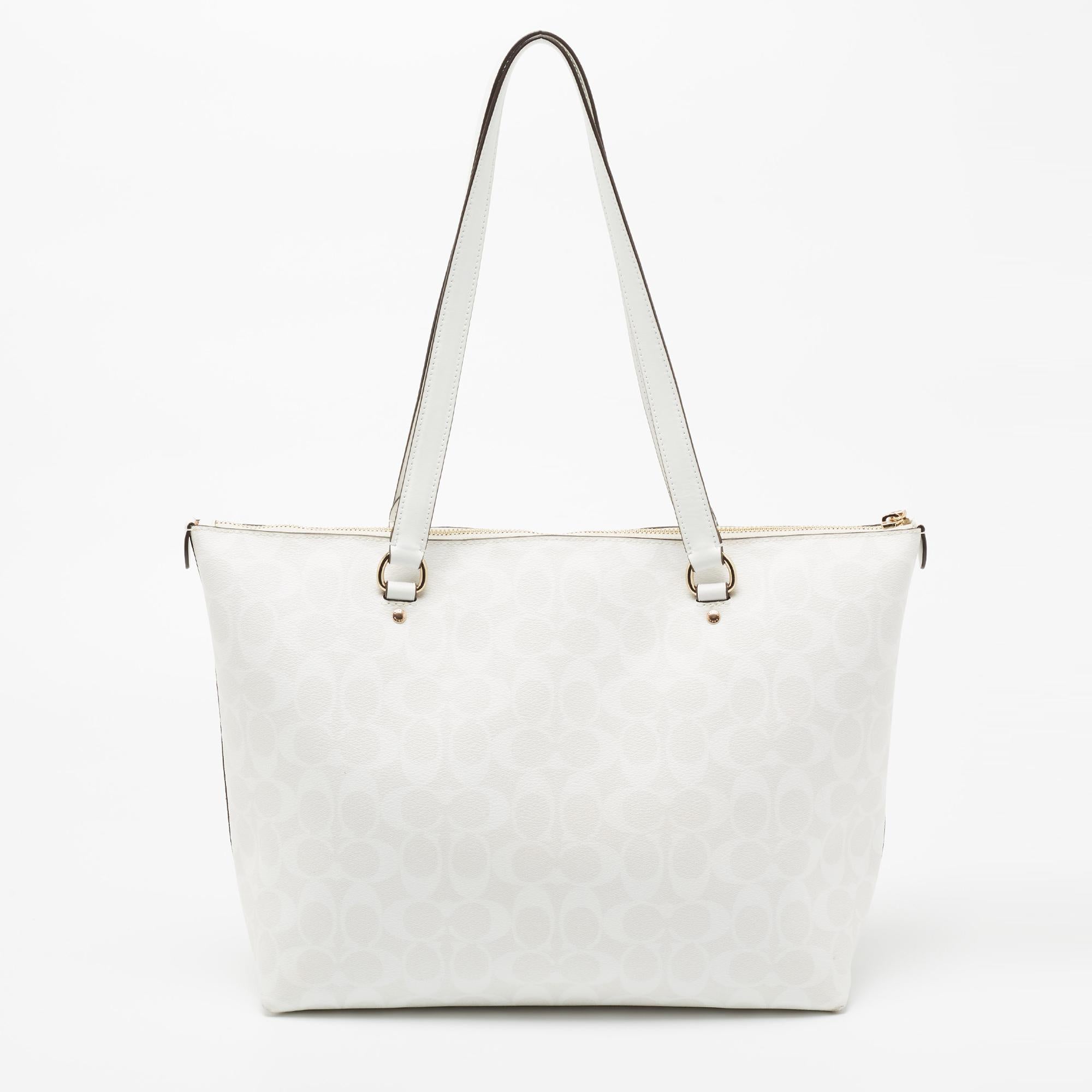 This designer tote from the House of Coach is super classy and functional, perfect for everyday use. It is made from signature coated canvas and leather with a gold-toned logo accent and zip pocket adorning the front. It has two shoulder