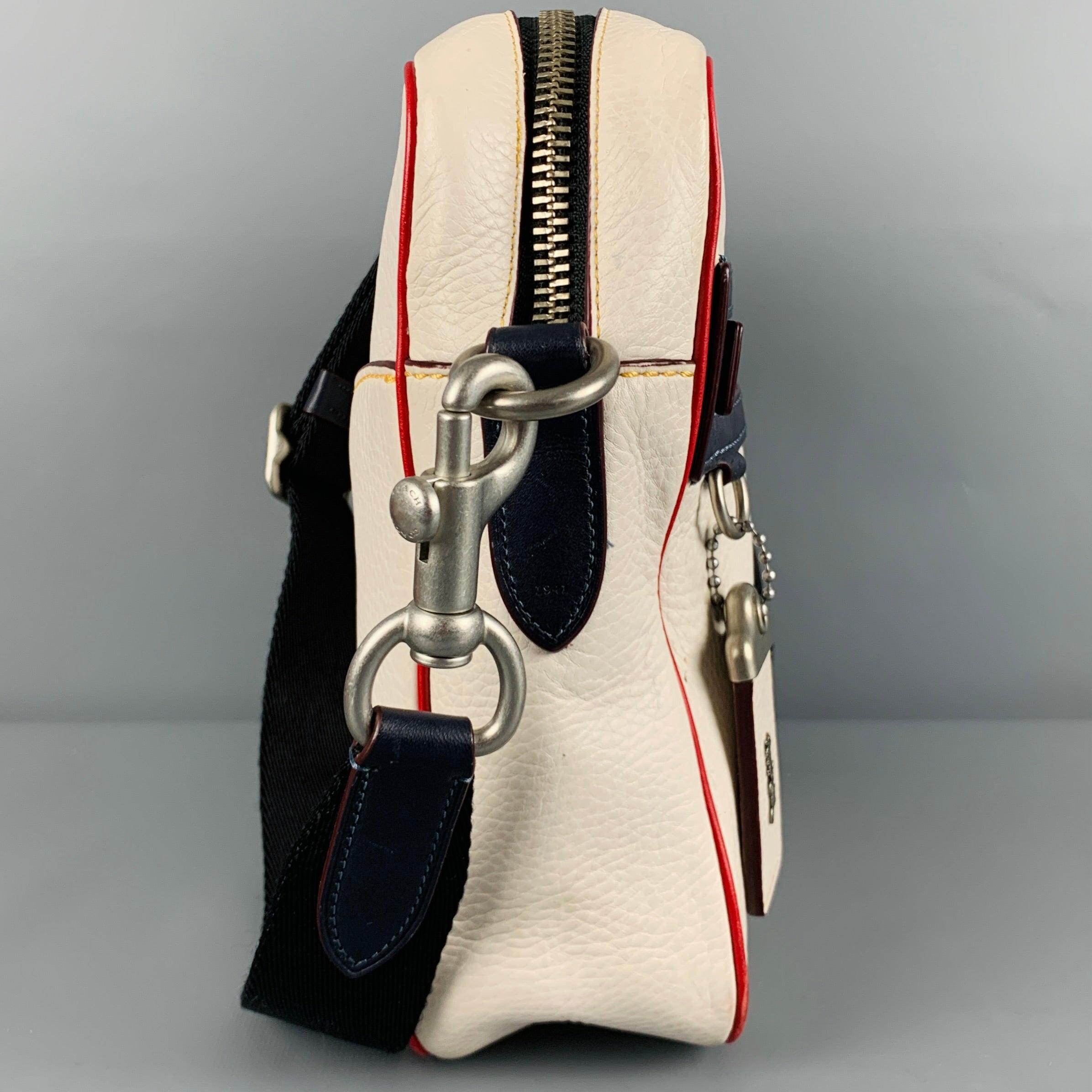 COACH x NASA bag
in a white glovetanned pebble grain leather fabric featuring crossbody style with removable adjustable shoulder strap, multi-color NASA logo, navy and red leather trim, and zip closure.Very Good Pre-Owned Condition. Minor marks.