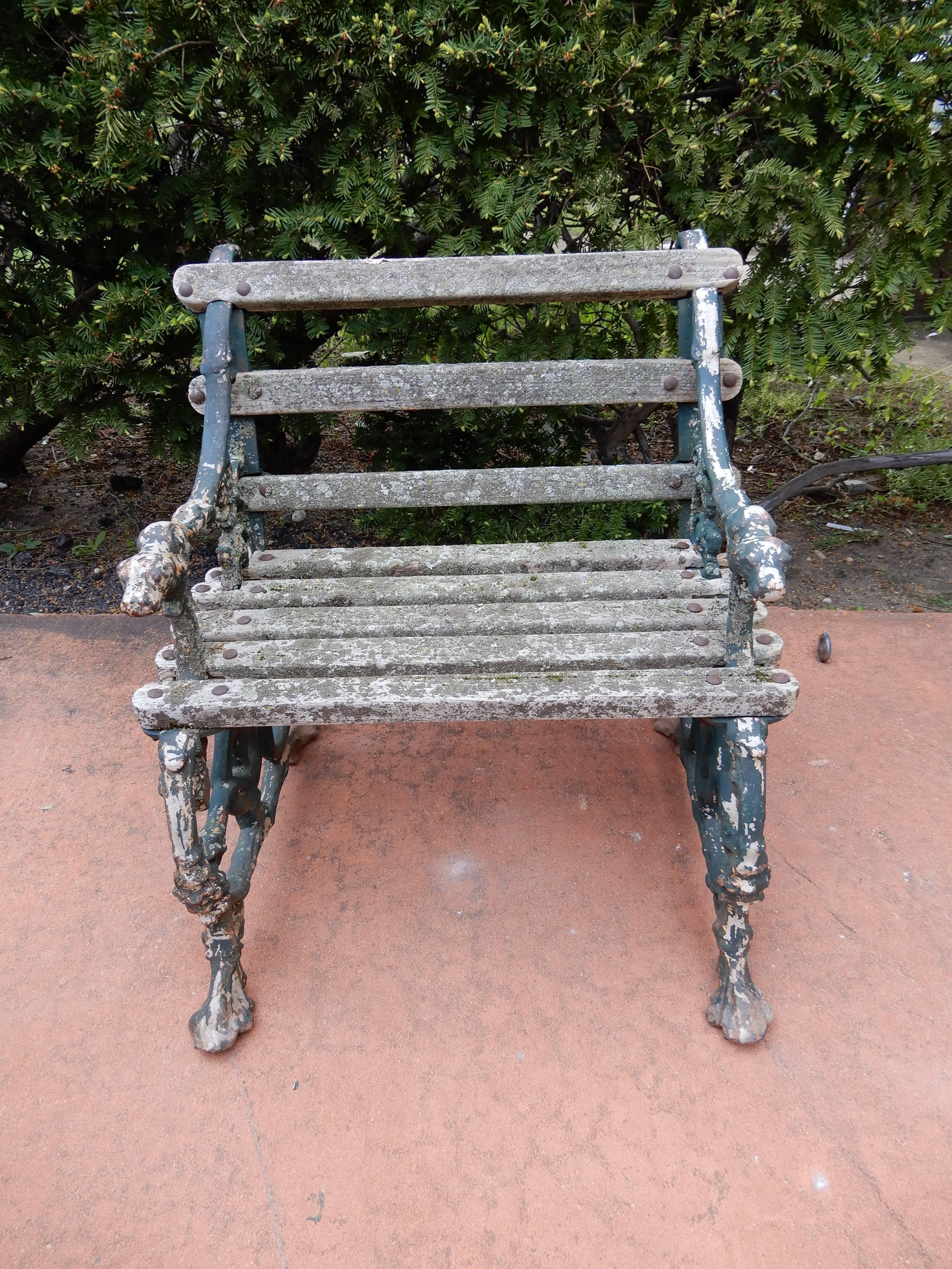 A late 19th century cast iron and wood seat garden chair by Coalbrookdale
The garden chair maintains an old worn painted finish on the cast iron a dark blue/black color. The motif of the desirable chair are the arms that terminate in dog heads, and