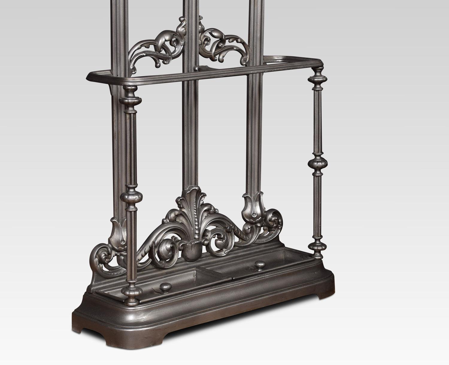 Victorian cast iron hall stand, the shaped arched top flanked by nine scrolling coat hooks, the lower section with cast iron shaped bar to receive sticks and umbrellas, the base with original drip trays and raised on shaped