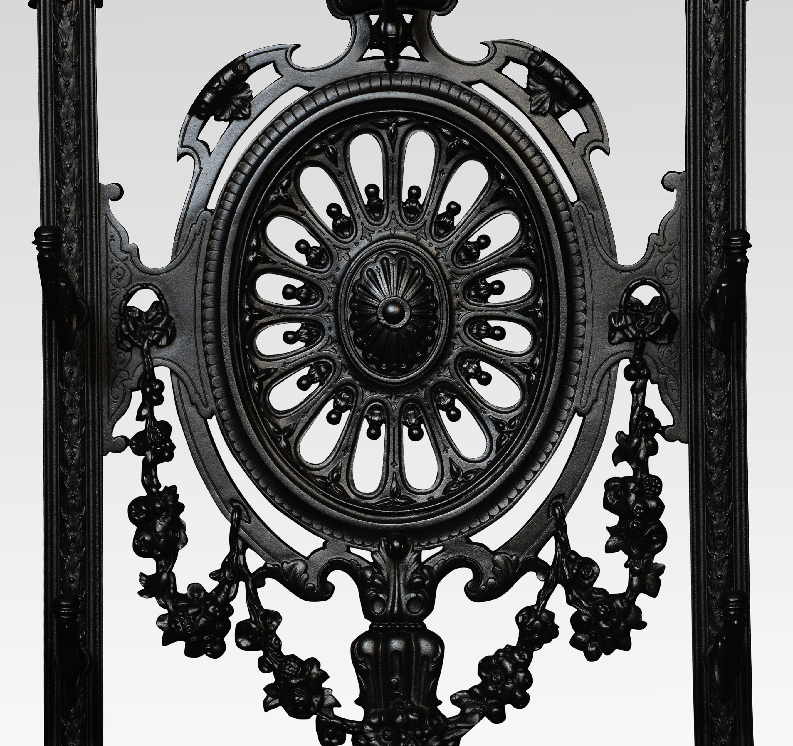 Coalbrookdale-style cast iron hall stand, of arched form, with eight scrolled hooks, the central pierced oval with cast leaf and fruit swags, over twin umbrella compartments, scroll and lattice detail above a pair of detachable drip trays, bearing