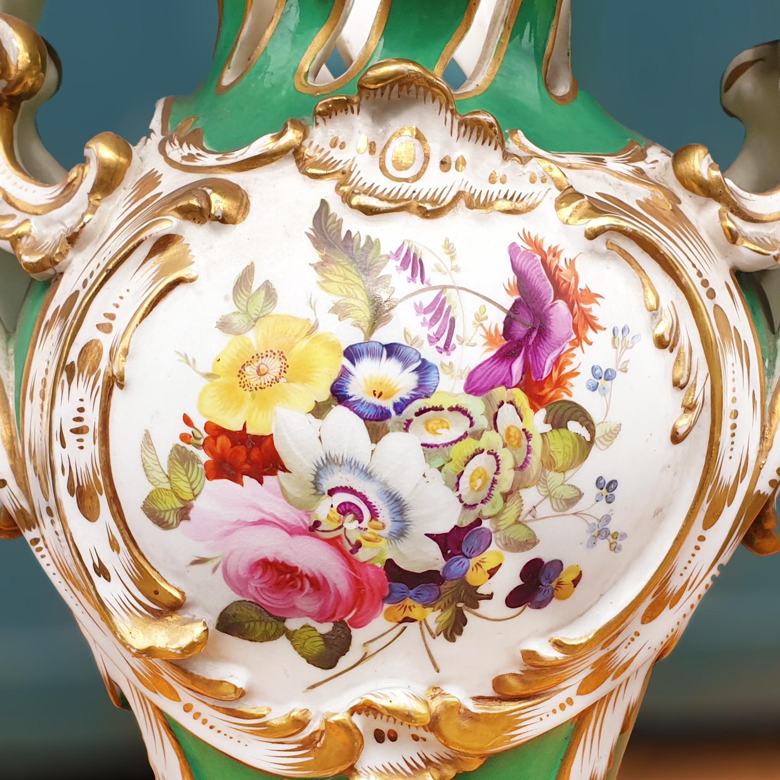 An impressive Coalport Vase with a beautiful hand painted floral cartouche of summer flowers in front and back panels set within a green ground. The vase of oval form presents with a short pierced neck that rises to form a very corrugated top rim