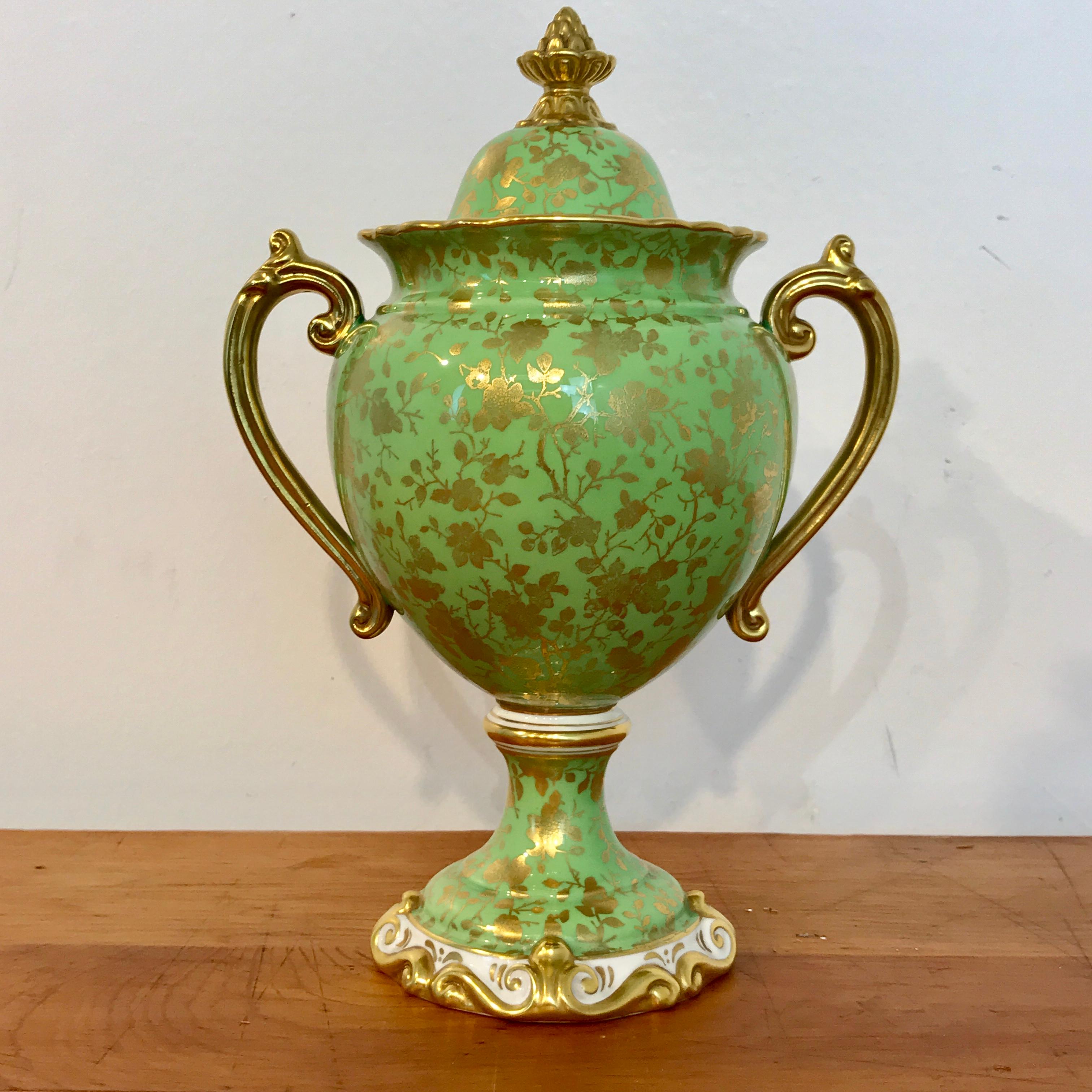 Coalport bone china covered gilt decorated covered urn, with apple green background, all-over sprays of gilt florals, signed with green backstamp and numbered V7948/3. The top diameter is 2.5