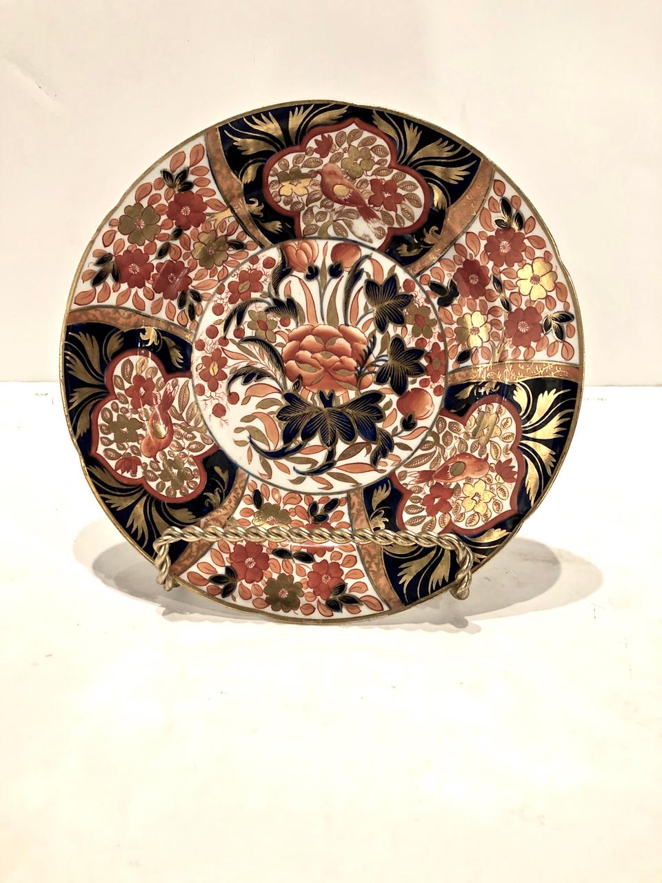 This is a pair of early 19th century Coalport dinner plates in an uncommon Imari pattern. The plates are densely decorated with a center reserve of an abstract peony surrounded by large reserves of birds and florals. The deep cobalt and iron red is