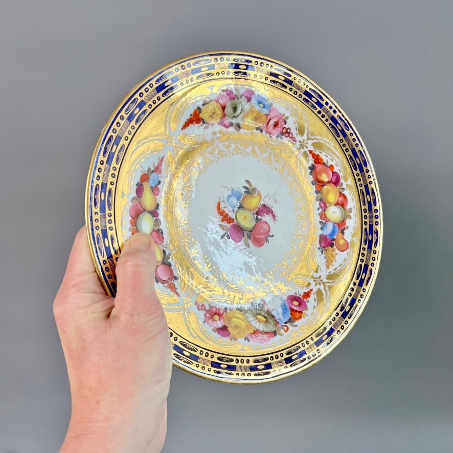 Dies ist ein wunderschöner Teller, der zwischen 1805 und 1815 von John Rose in Coalport hergestellt wurde. Der Teller ist mit kobaltblauer Unterglasurmalerei verziert und hat wunderschöne handgemalte Blumen und Früchte sowie eine reiche