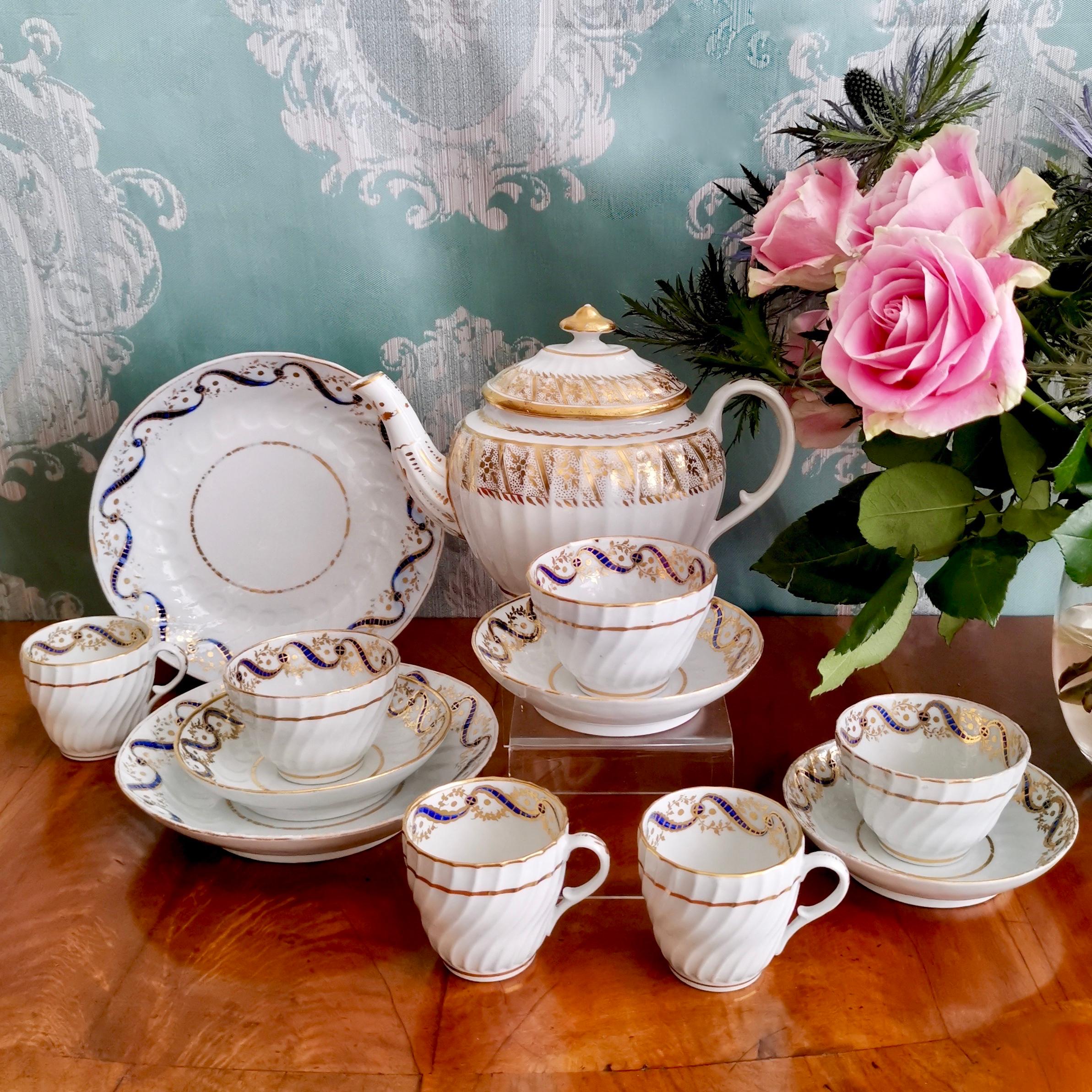 This is a beautiful tea service made by John Rose (Early Coalport) in circa 1795, which was the Georgian era. The service is beautiful white with gilt decorations and it consists of a lidded teapot, two cake plates, and three trios each consisting