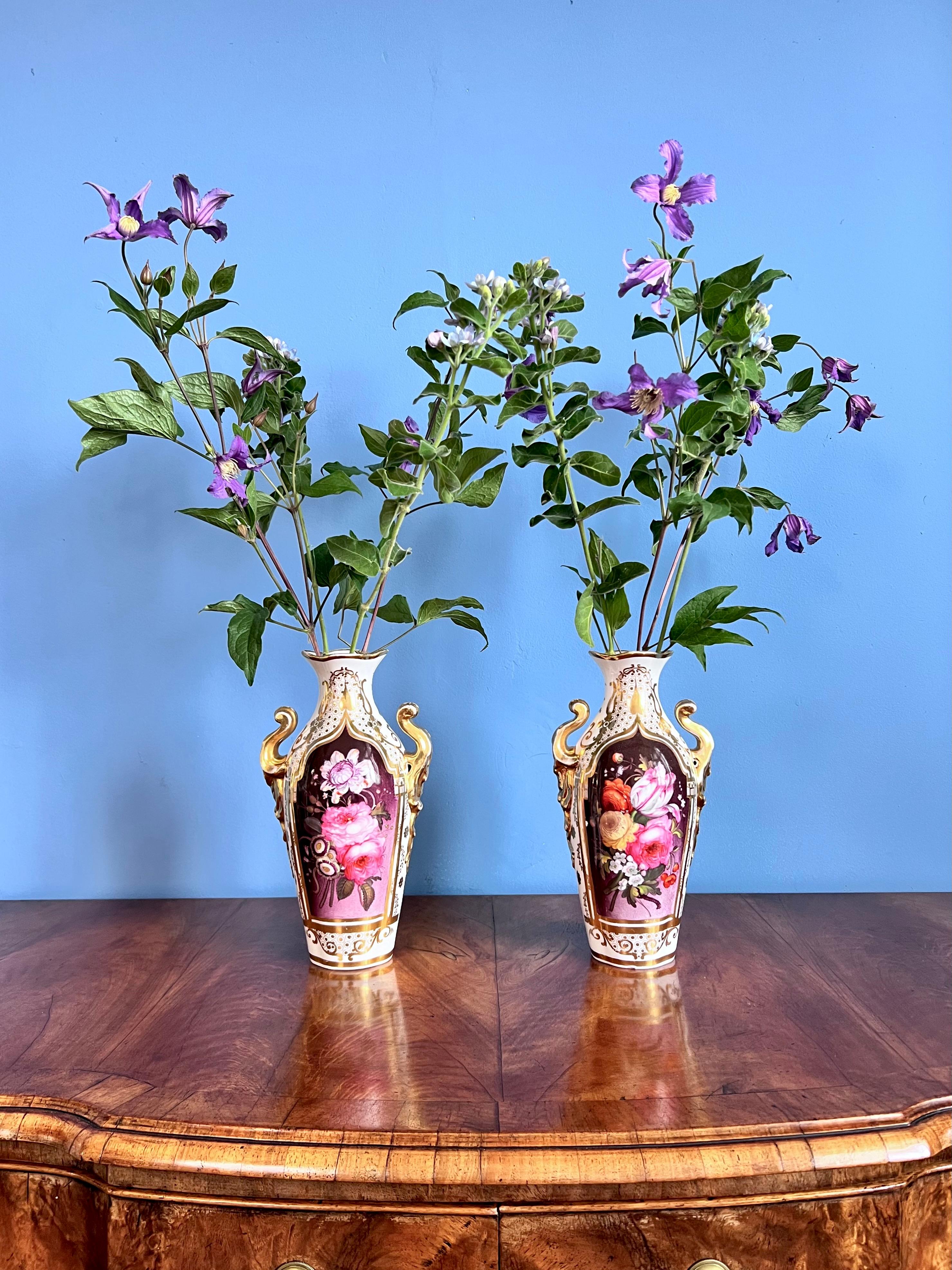 This is a stunning and very rare pair of vases made by Coalport in around 1845. The vases have rich gilding in the Persian Revival style, combined with very English floral reserves of freely painted flower bouquets on a puce ground. Incorporated