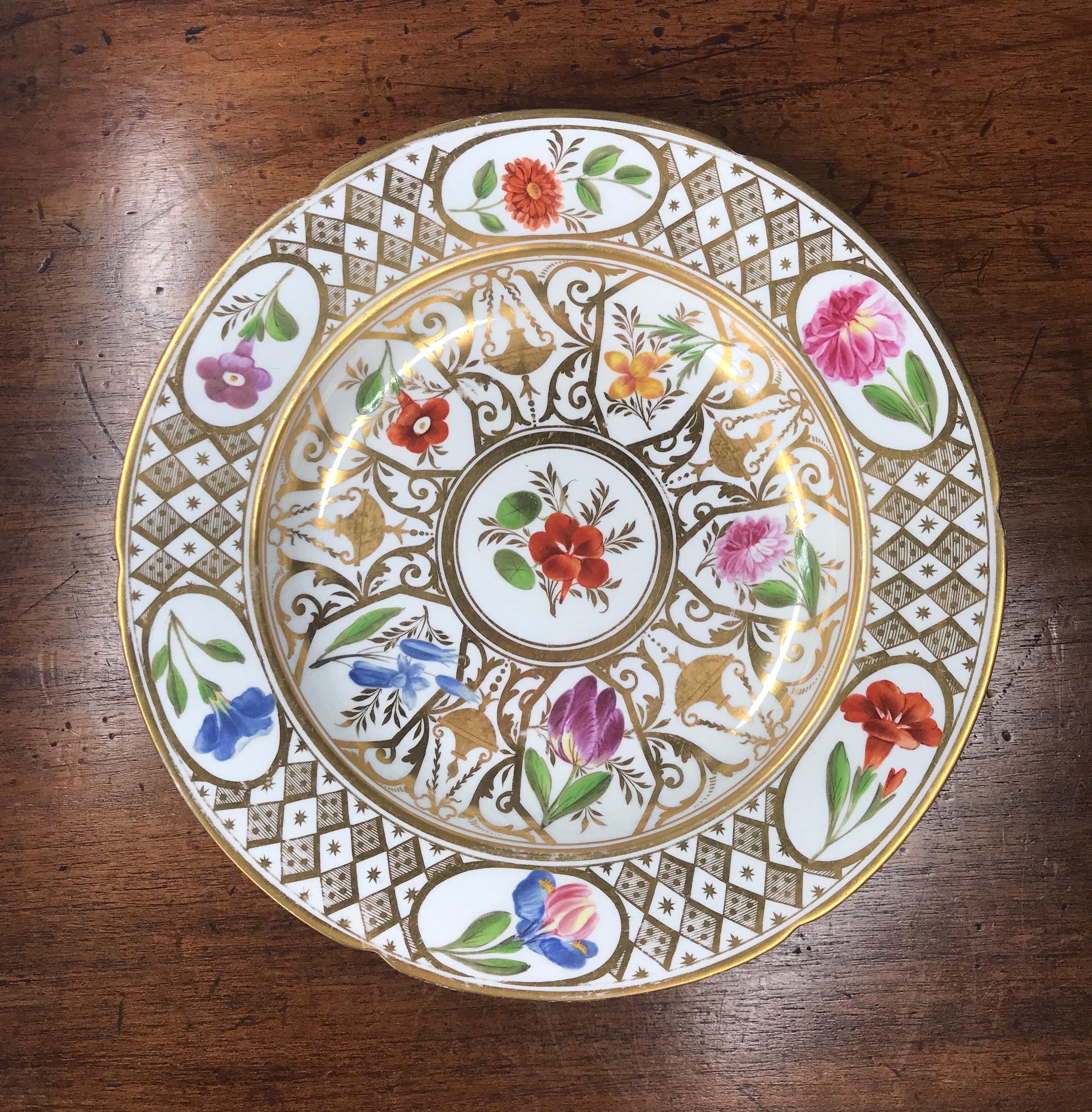 Coalport plate of slightly lobed form, richly decorated in the Baxter Baxter Studio with flower specimens including tulips, nasturtiums, irises and roses, set in shaped panels, the centre with rich gilt frieze including hanging lamps and scrollwork,