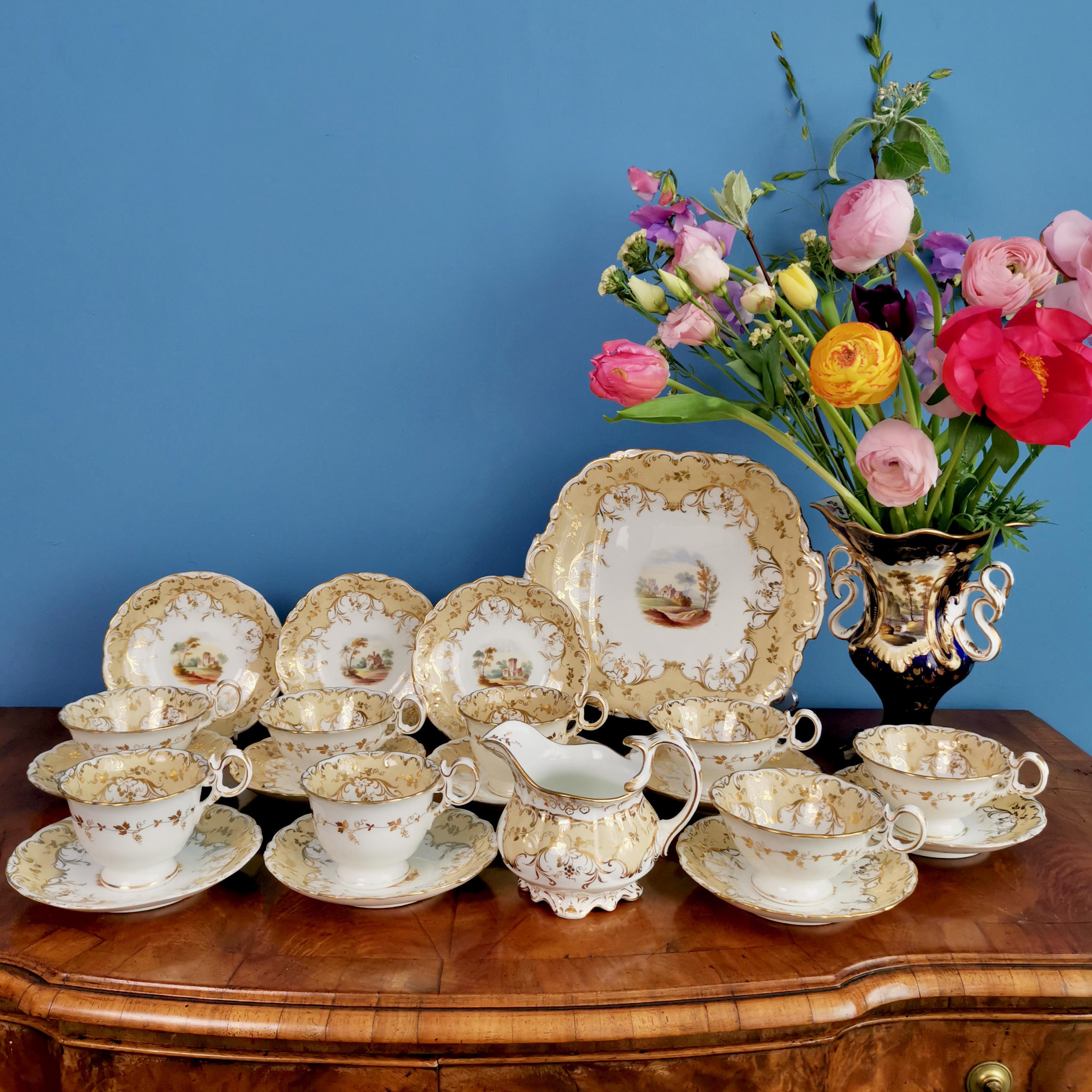 This is a beautiful coffee cup and saucer made by Coalport in 1840, which was the Rococo Revival period. The set is decorated with a warm beige ground with gilt floral patterns and beautiful hand painted landscapes. It was made in the famous