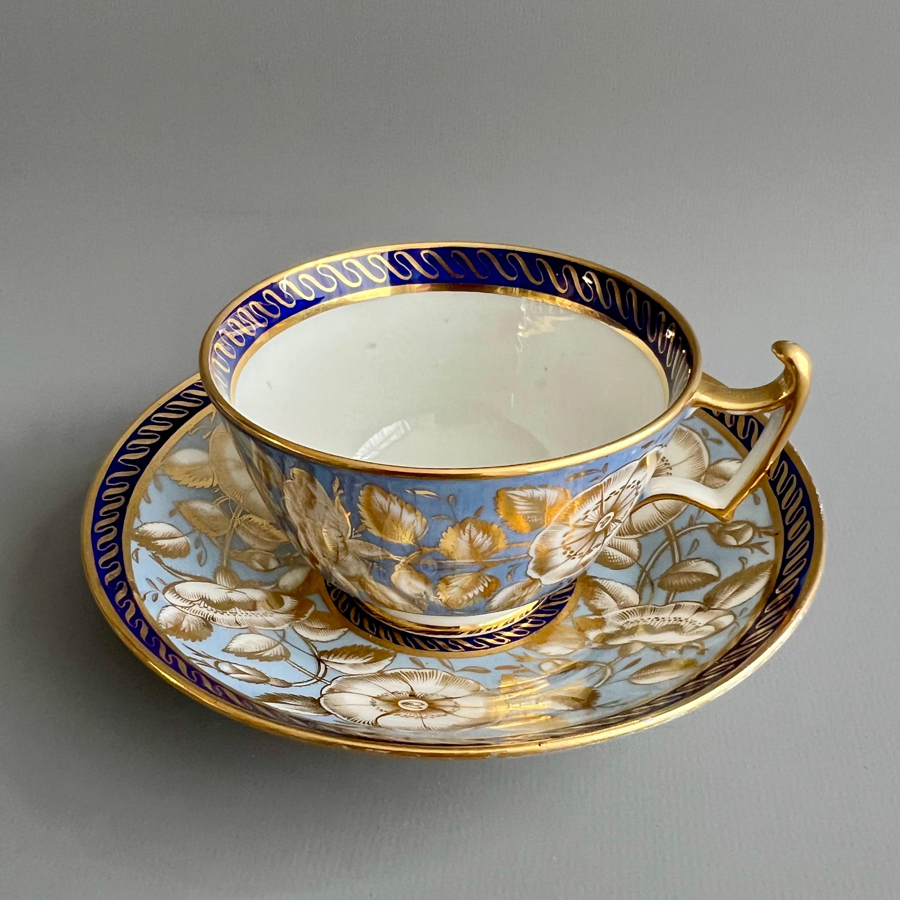 This is a beautiful teacup and saucer made by John Rose / Coalport in about 1815, which was the Regency era. The set is decorated in a gorgeous periwinkle blue ground with rich gilt and white wild roses and a cobalt blue rim with gilt.

Coalport
