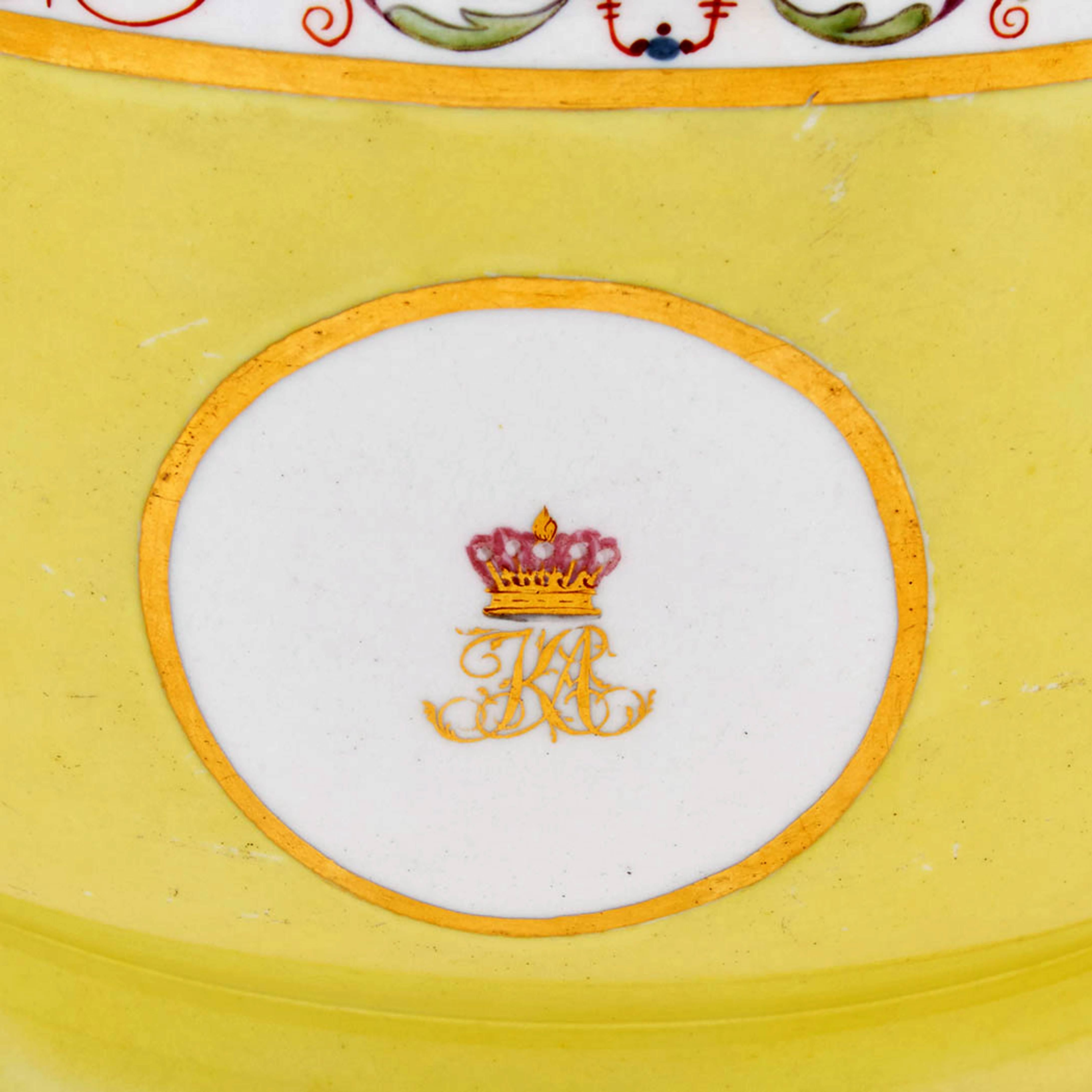 Coalport porcelain yellow-ground wine coolers, 
circa 1800-1810.

Each circular yellow-ground porcelain wine cooler has a polychrome scrolling foliate and urn band above a crest of an Earl with a crown above a monogram of interlaced KA.

The