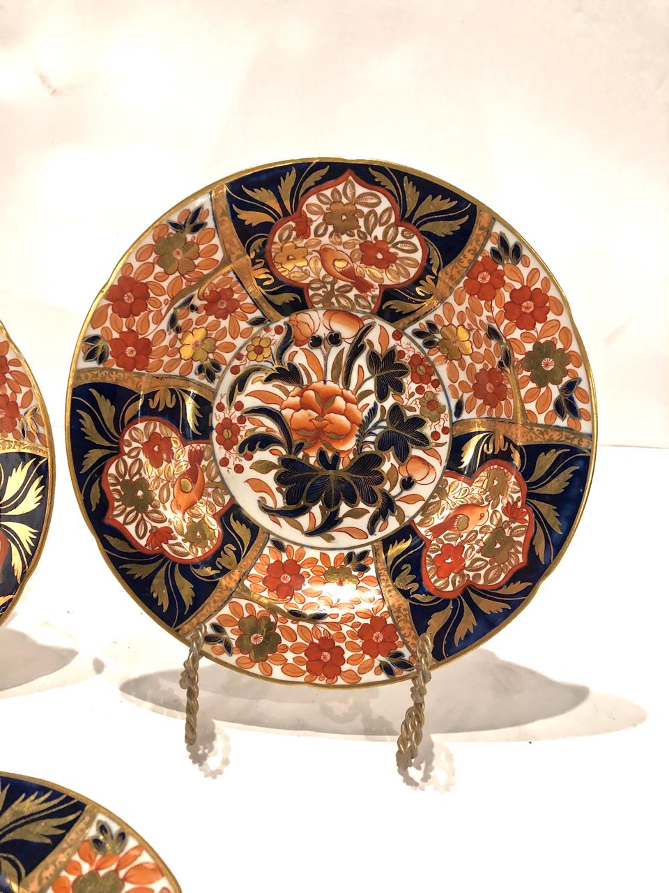 This is a set of three of early 19th century Coalport soup plates in an uncommon Imari pattern. The plates are densely decorated with a center reserve of an abstract peony surrounded by large reserves of birds and florals. The deep cobalt and iron