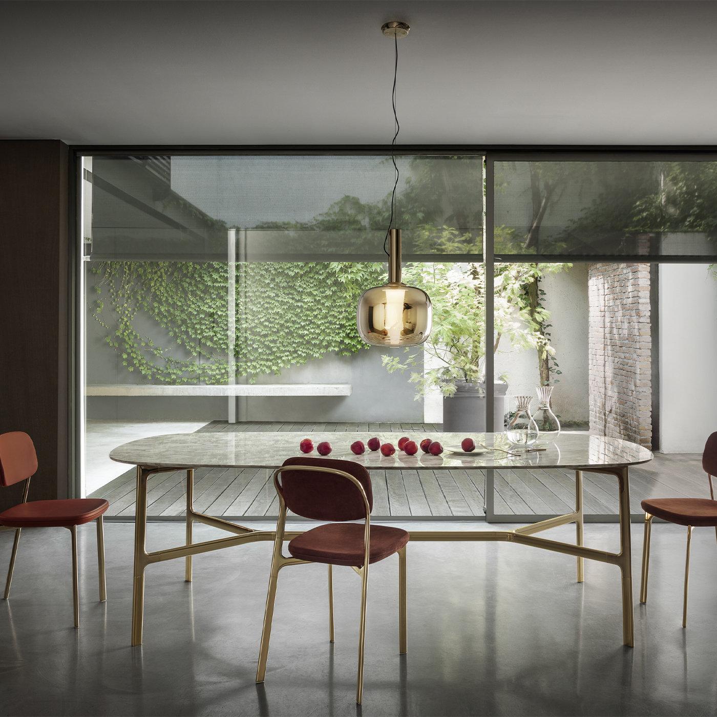 El refinado marco de latón pulido o bruñido y la escultural carpintería de esta mesa sostienen un tablero de mármol Calacatta Gold con esquinas redondeadas, creando una silueta arquitectónica y orgánica a la vez. El resultado es una superficie