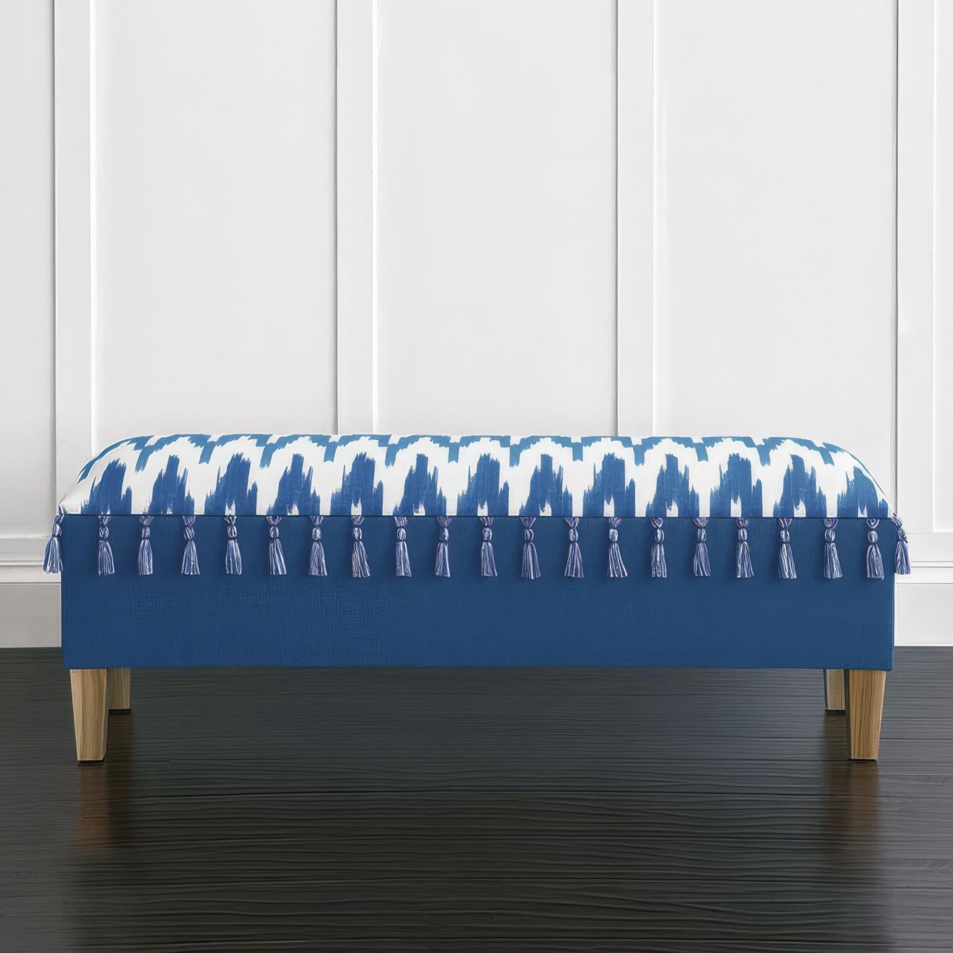 Panca imbottita, un mix perfetto di arte e funzionalità. Il cuscino Sombori Cerulean con motivo ikat aggiunge vivacità, mentre le nappe artigianali e la base Amador Ocean creano un contrasto raffinato. Poggiata su gambe affusolate in legno naturale,