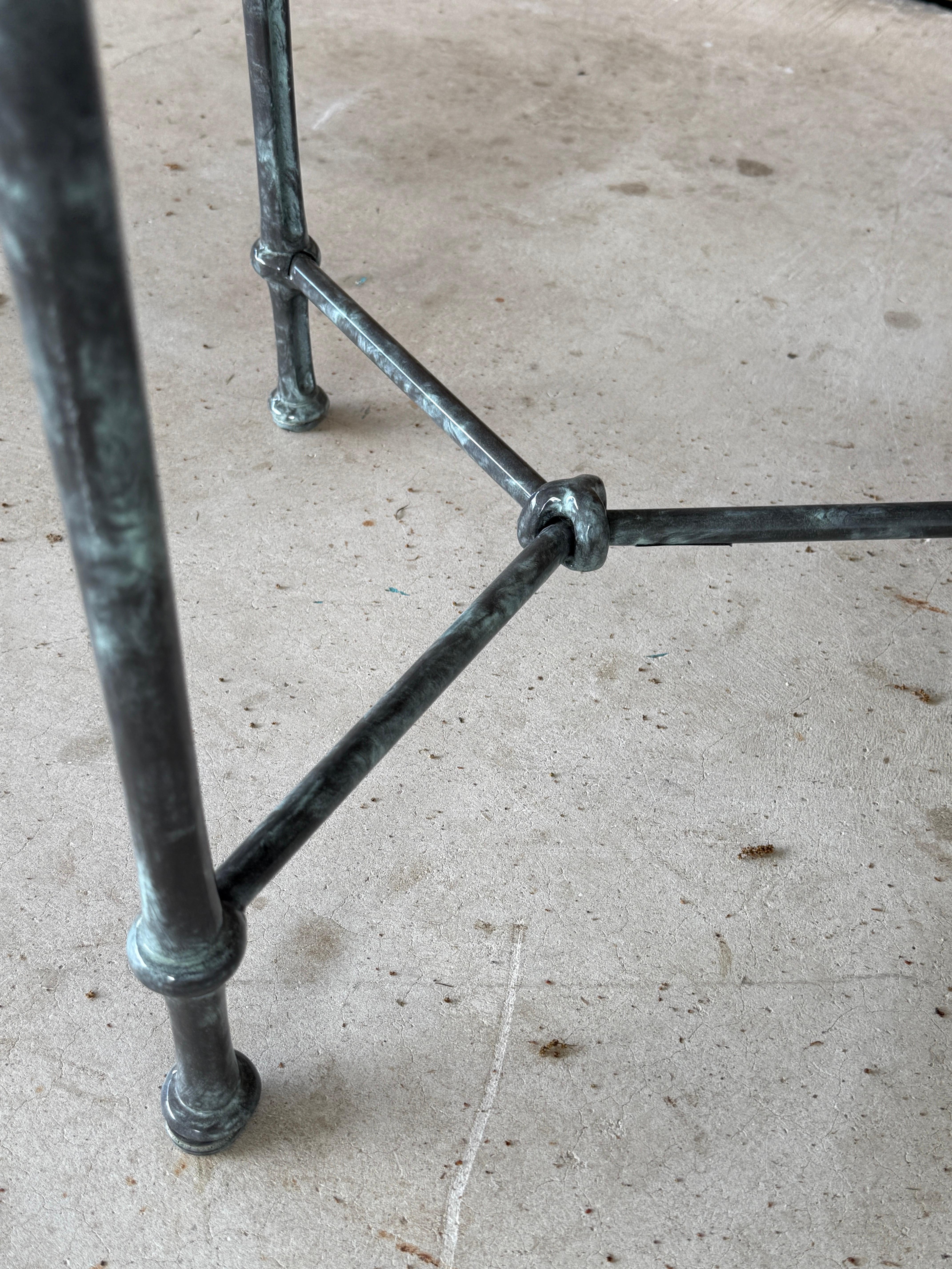 A timeless pair of vintage outdoor side tables by Brown Jordan, featuring an aluminum frame with an original faux verdigris marble finish.
The round glass tops rest within the elegant metal frame, which is designed in a sleek straight style, knotted