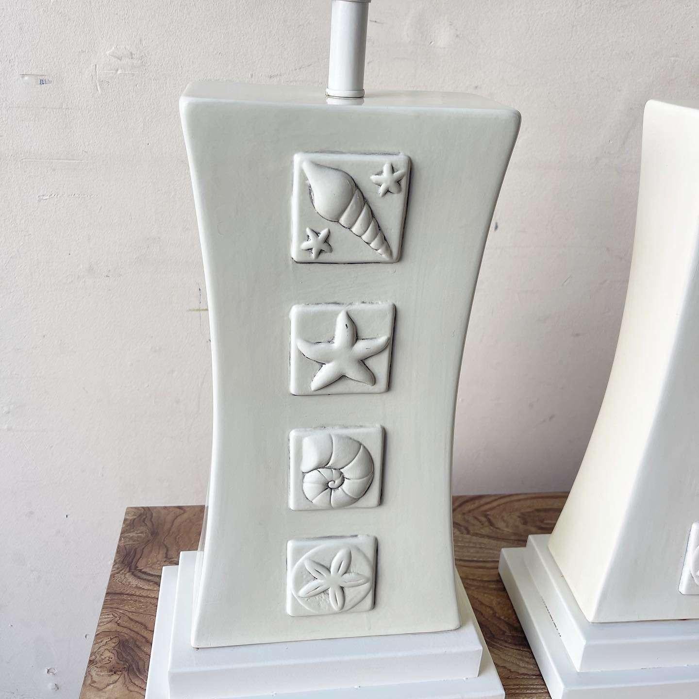 Illuminez votre espace avec le charme du bord de mer de cette paire de lampes de table en céramique Coastal Cream Sea Shell. Chaque lampe est magnifiquement fabriquée avec une base en céramique qui présente des motifs complexes de coquillages,