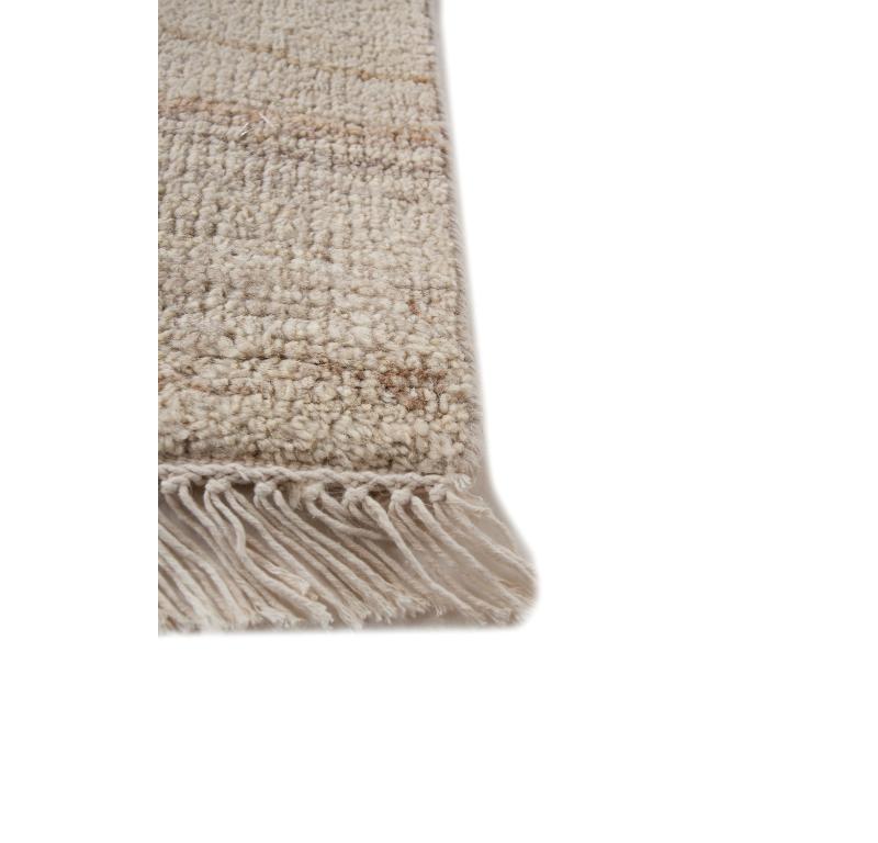 Introducing this hand-knotted rug  with a minimalist design that captures the essence of tranquility. The antique white ground color, paired with a border in medium gold, evokes a sense of elegance. At a glance, it resembles beach sand gracefully