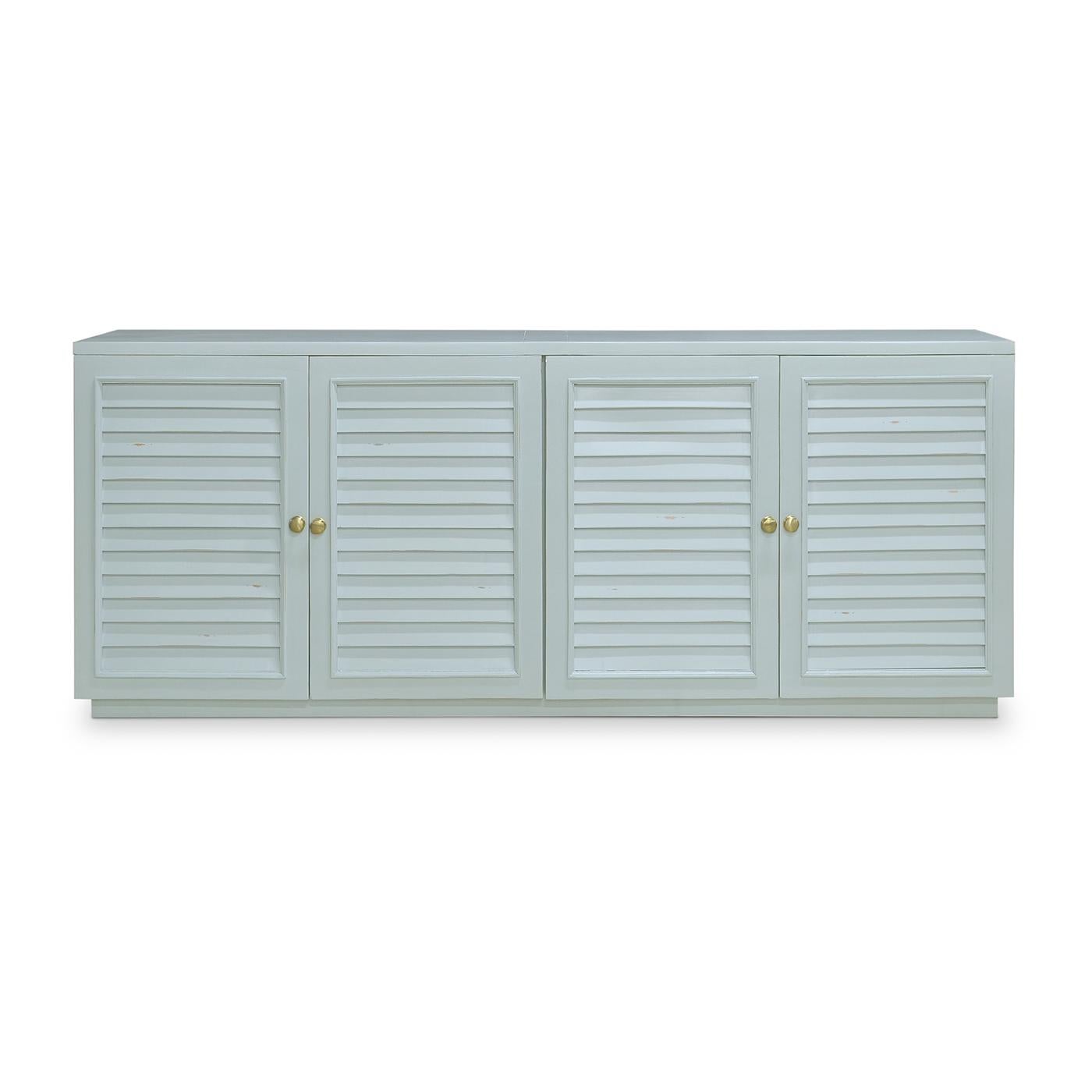 A stunning piece that exudes coastal charm in a lightly distressed Ocean Blue finish. This exquisite sideboard, crafted from solid mahogany, features plantation shutter-style cupboard doors and elegant brass knobs, blending sophisticated style with