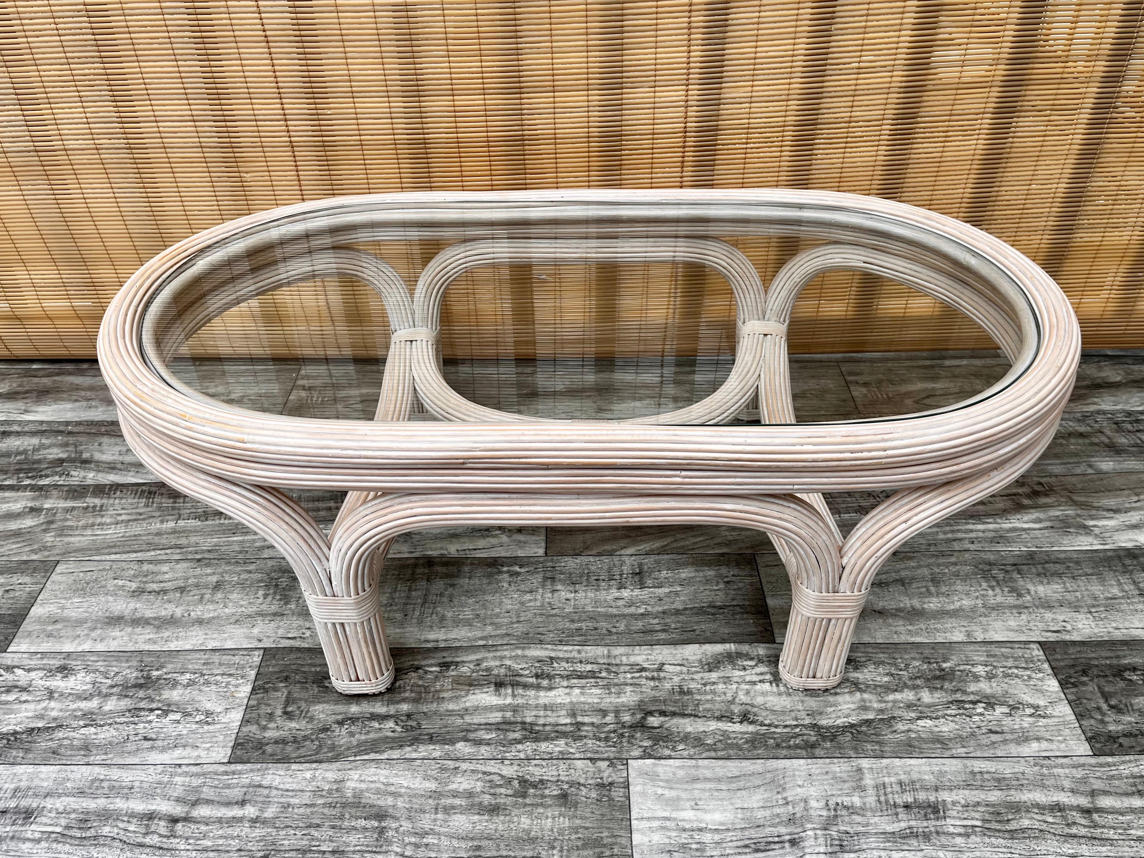 Vintage Coastal Style pencil reed coffee table in the Gabriella Crespi Style. circa 1980s 
Features sophisticated curves, an elegant rattan pencil reed construction in white washed finish and an oval glass top.
In excellent near mint original