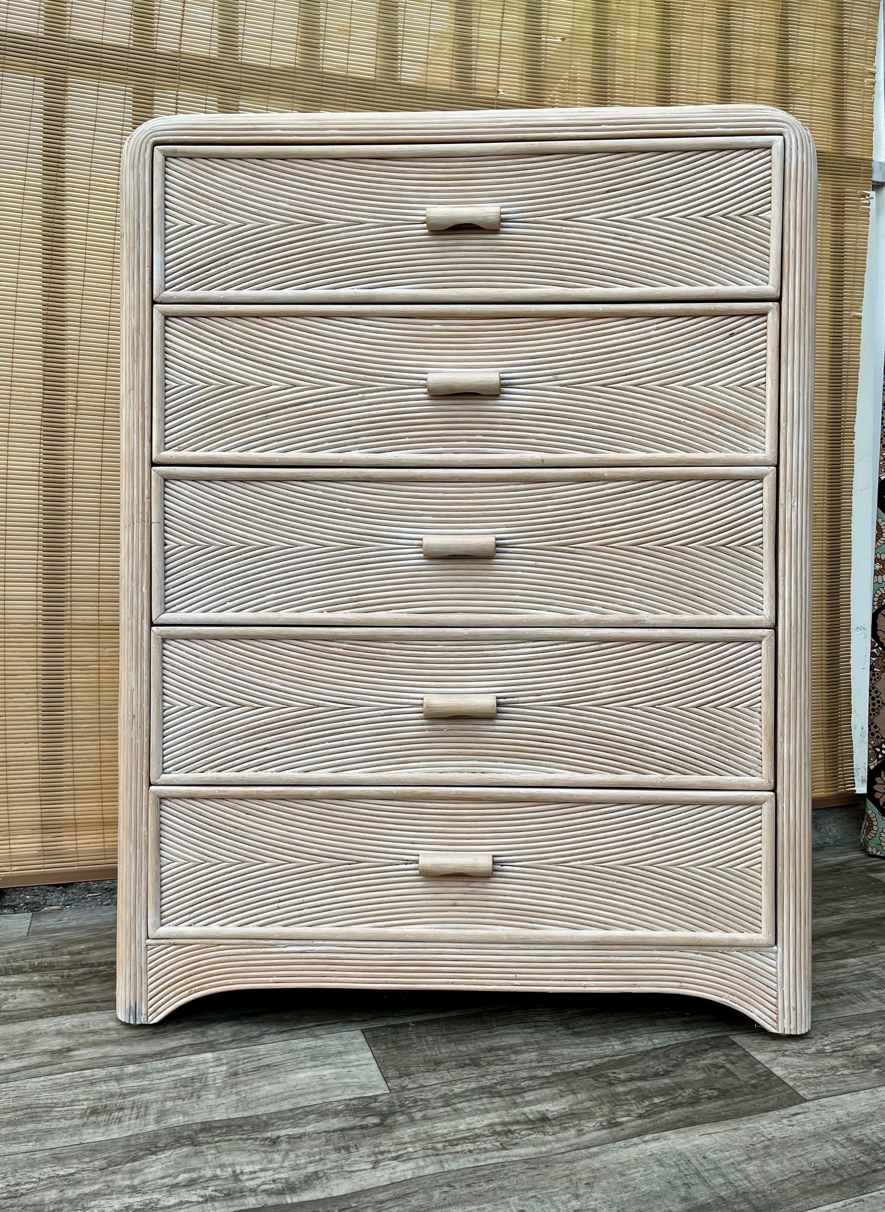 Coastal Style Pencil Reed Highboy Dresser. circa 1980s
Features a chic rattan and split pencil reed swirl pattern design with rounded corners in a beautiful soft cream color with 5 drawers that offer plenty of storage space.
In good original