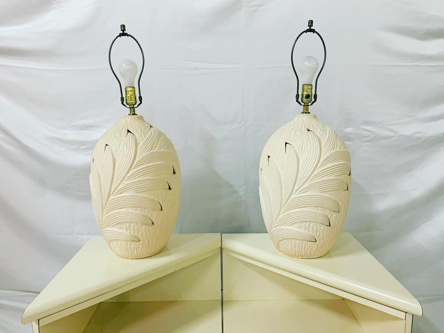 Vintage pair of 80s table lamps in Serge Roche styling made by Harris lamp company. Large urn shaped bases are done of all beige plaster decorated with an overlapping bas relief palm frond leaf pattern. They are signed at the base with ‘Harris lamps