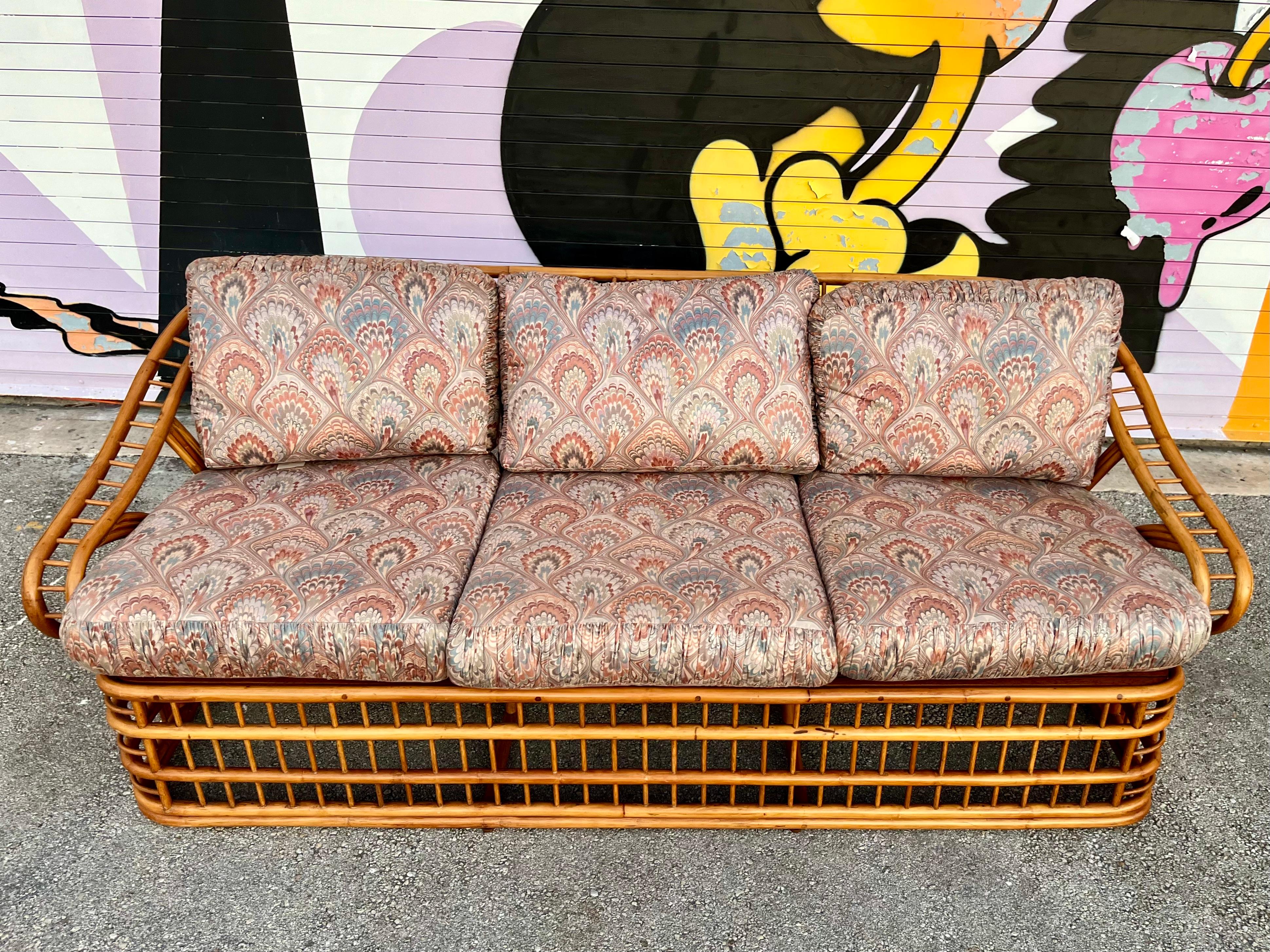 Vintage Coastal Style Rattan Three Seats Sofa by Whitecraft Rattan Inc, Miami FL. Circa 1970s
Features a bent rattan frame with an intricate and dynamic fluid design at the back and armrests. 
In excellent original condition with very minor sings of