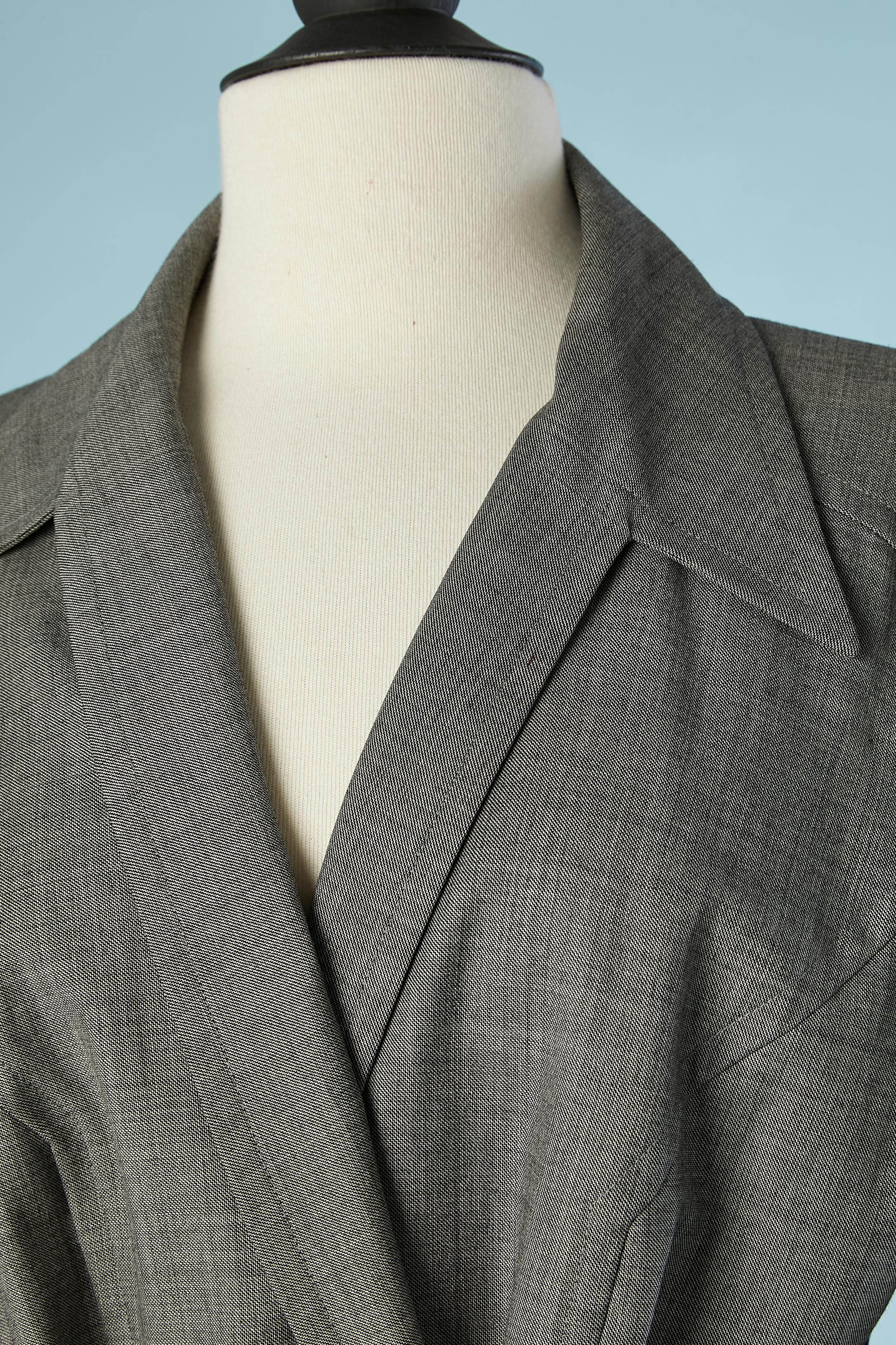 Completo di cappotto e pantaloni in lana grigia. Cintura sul cappotto, lunghezza= 140 cm. Non c'è fodera, ma tubature all'interno. Pieghe a scatola sulla parte centrale della schiena. 
Taglia 42 (It) 38 (Fr) M 