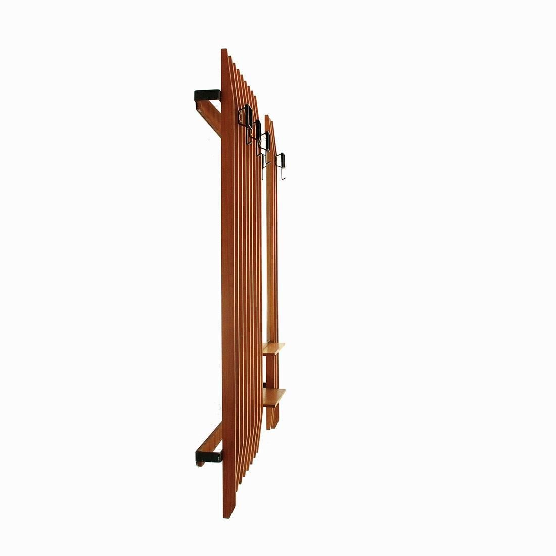 Coat hanger of Italian manufacture produced in the 1950s.
Structure consisting of two bars in black painted metal and teak strips with a tapered finish.
Hooks in black painted metal.
Mirror with upper and lower brass frame.
Two teak