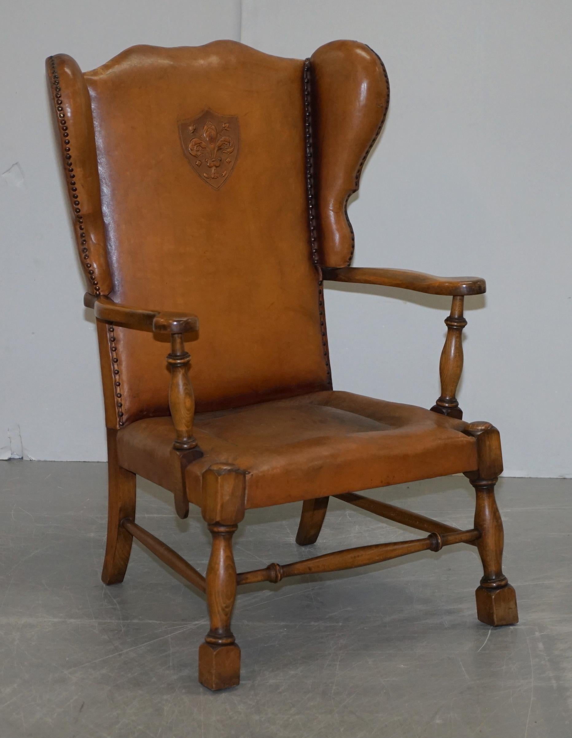 We are delighted to offer for sale this lovely pair of Edwardian wingback armchairs with oak frames and brown leather upholstery that have embossed coat of arms armorial crests in the back

These chairs have the original leather upholstery, one