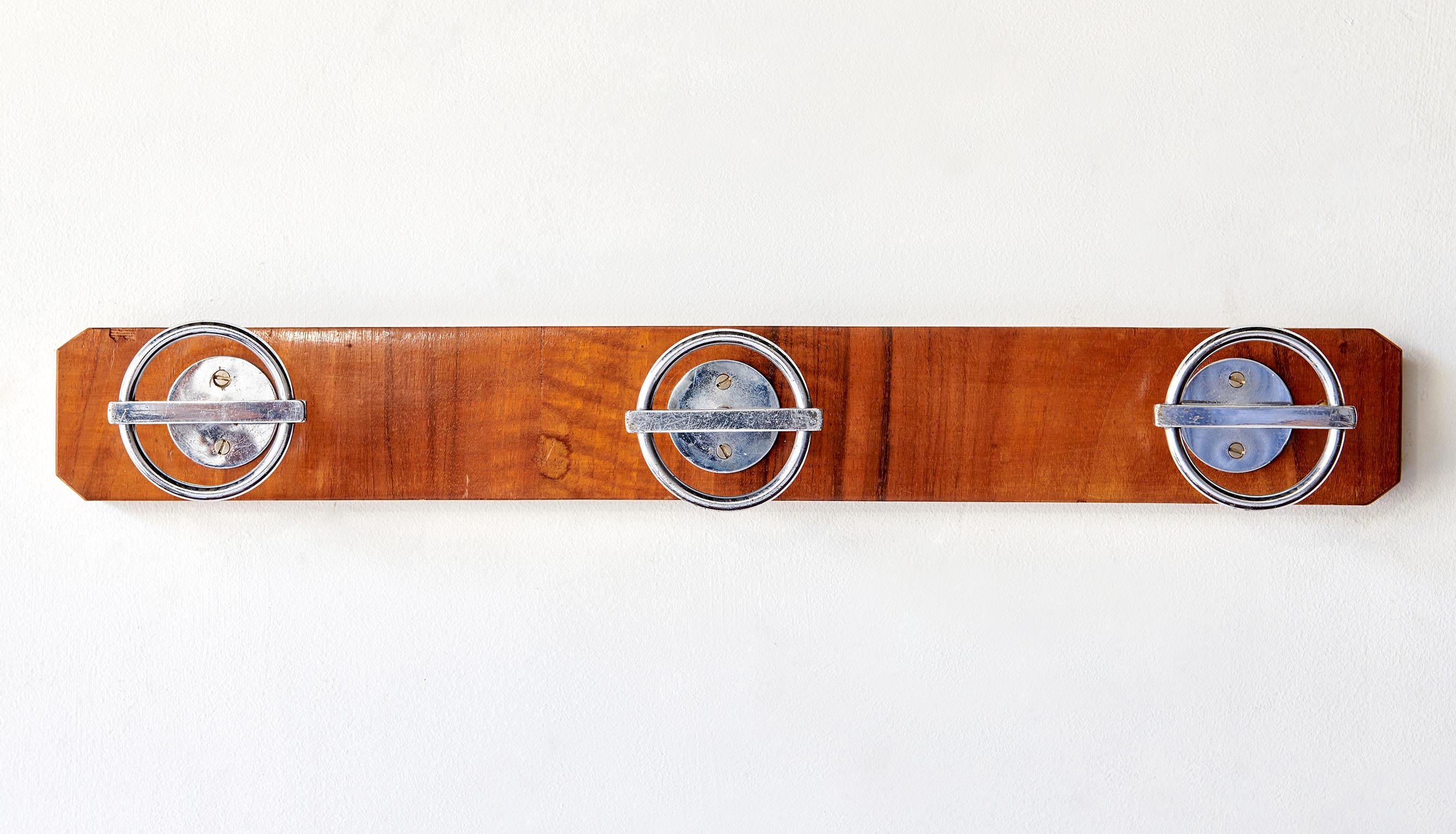 Made in the 1960s, this coat rack is a fruitwood-veneered wooden plank fitted with three nickel-plated brass patères (