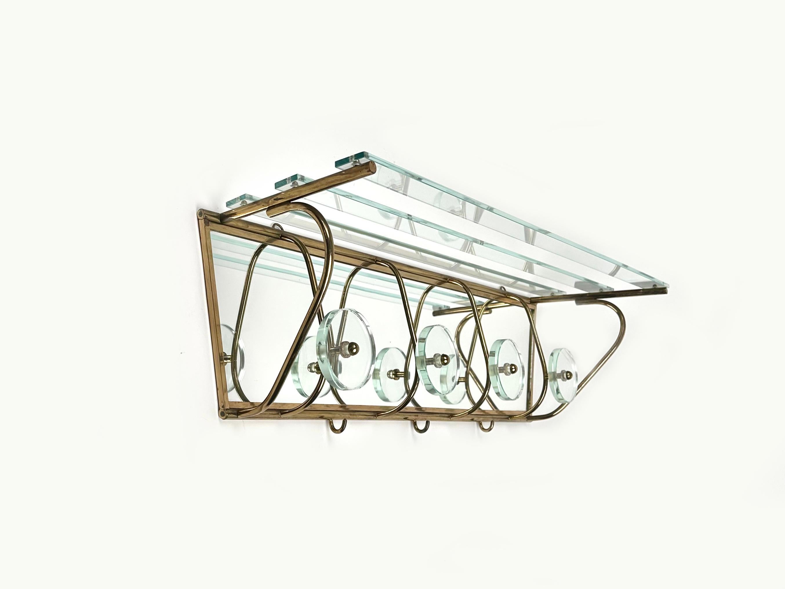 Wall-mounted coat rack in mirror with a top glass shelf supported by brass structure featuring four circular hooks in glass and brass in the style of Fontana Arte.

Made in Italy in the 1950s.