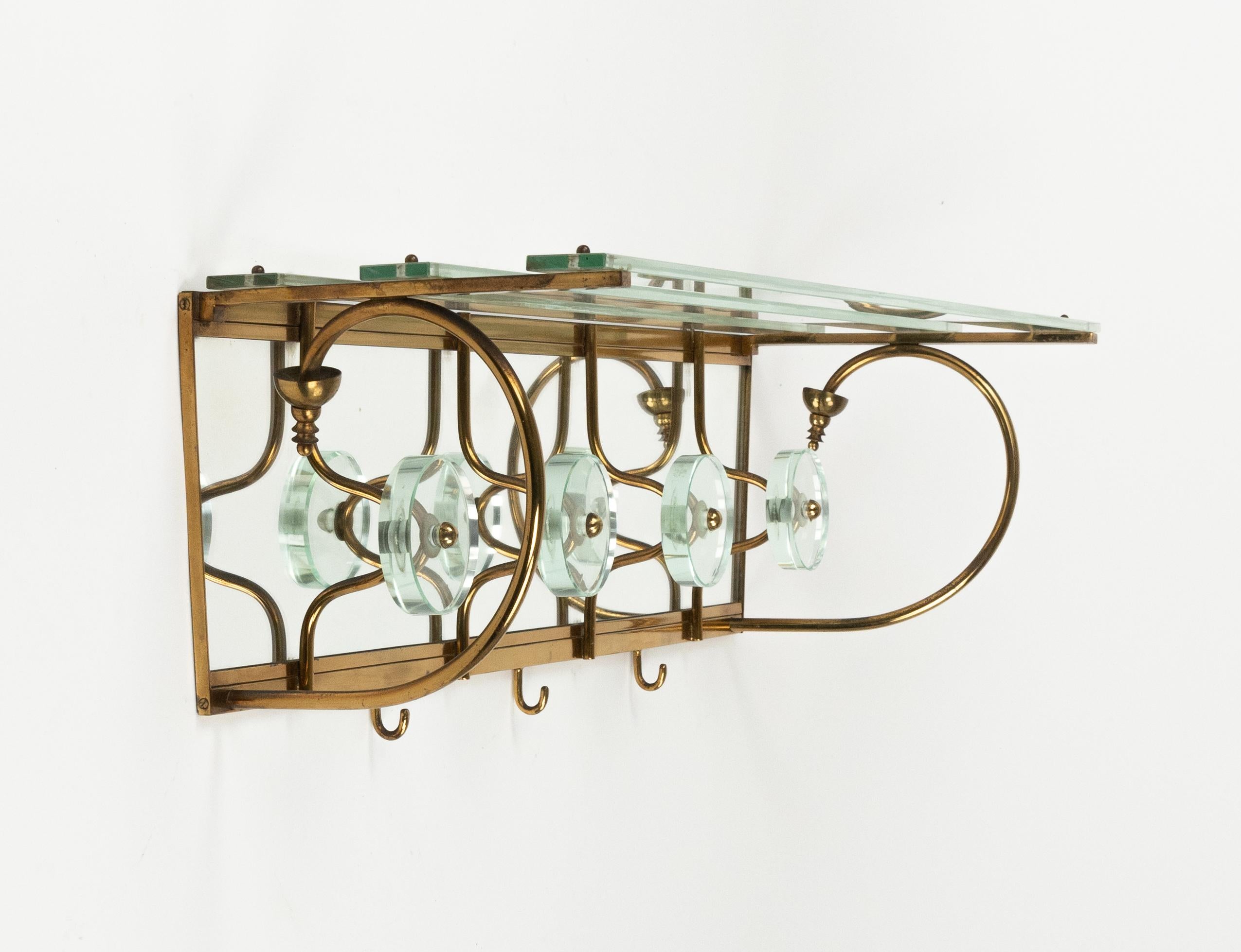 Schön aus der Jahrhundertmitte  Wandgarderobe aus Spiegel mit einer oberen Glasablage, die von einer Messingstruktur getragen wird, die vier runde Haken aus Glas und Messing im Stil von Fontana Arte aufweist.

Hergestellt in Italien in den 1950er