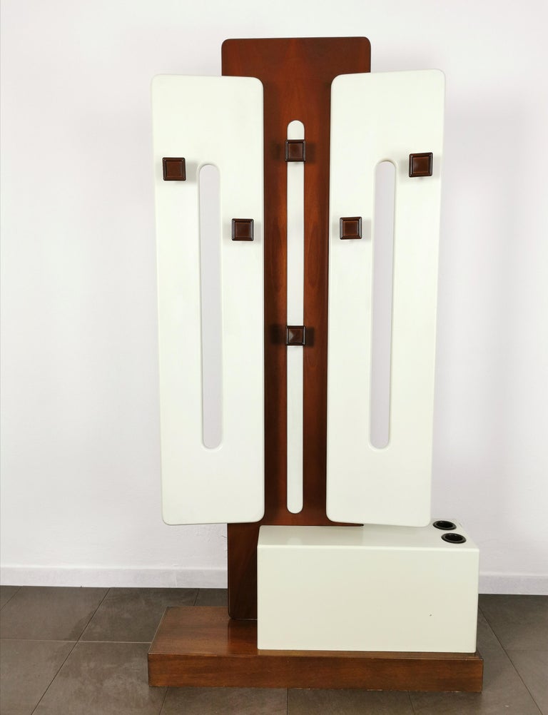 Particular multifunctional coat rack produced by the Italian designer Luigi Sormani in the 70s. The coat rack was made of white and brown lacquered wood with two folding doors, 6 square-shaped hangers on the front, 2 circular-shaped hangers on the