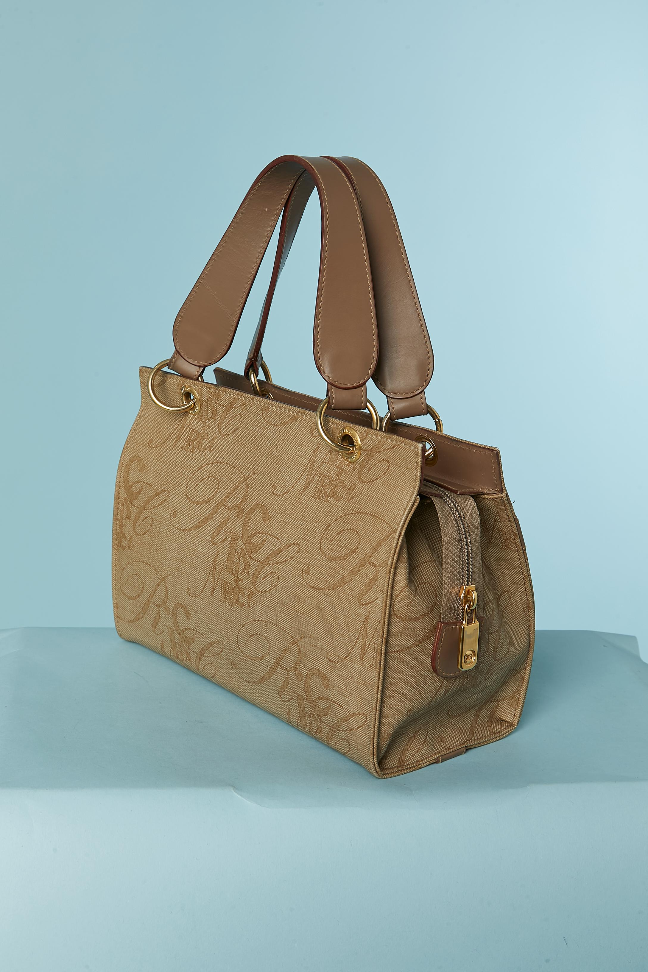 Coated and branded canevas and leather top handle bag. One flat pocket on the front of the bag + one inside pocket with zip closure. Zip closure on the top middle front whit branded zip puller.
SIZE 24cm X 18cm X 12cm 
Handle lenght = 34cm 