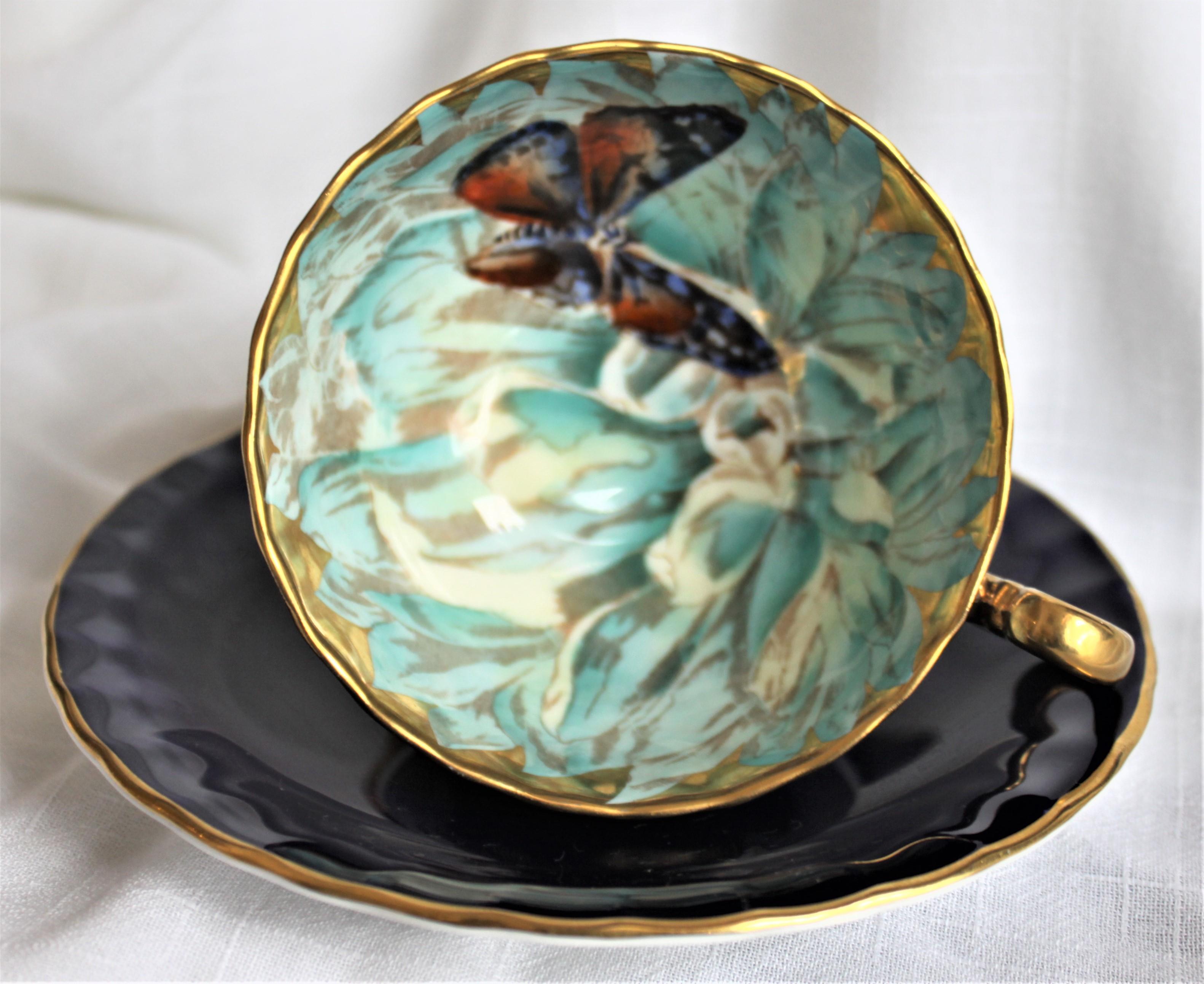This very intricately hand painted tea cup and saucer set is made of fine bone china by the Aynsley factory of England. As presented in the photos, the bowl of the cup is done with a very well executed hand painted butterfly in a background of white
