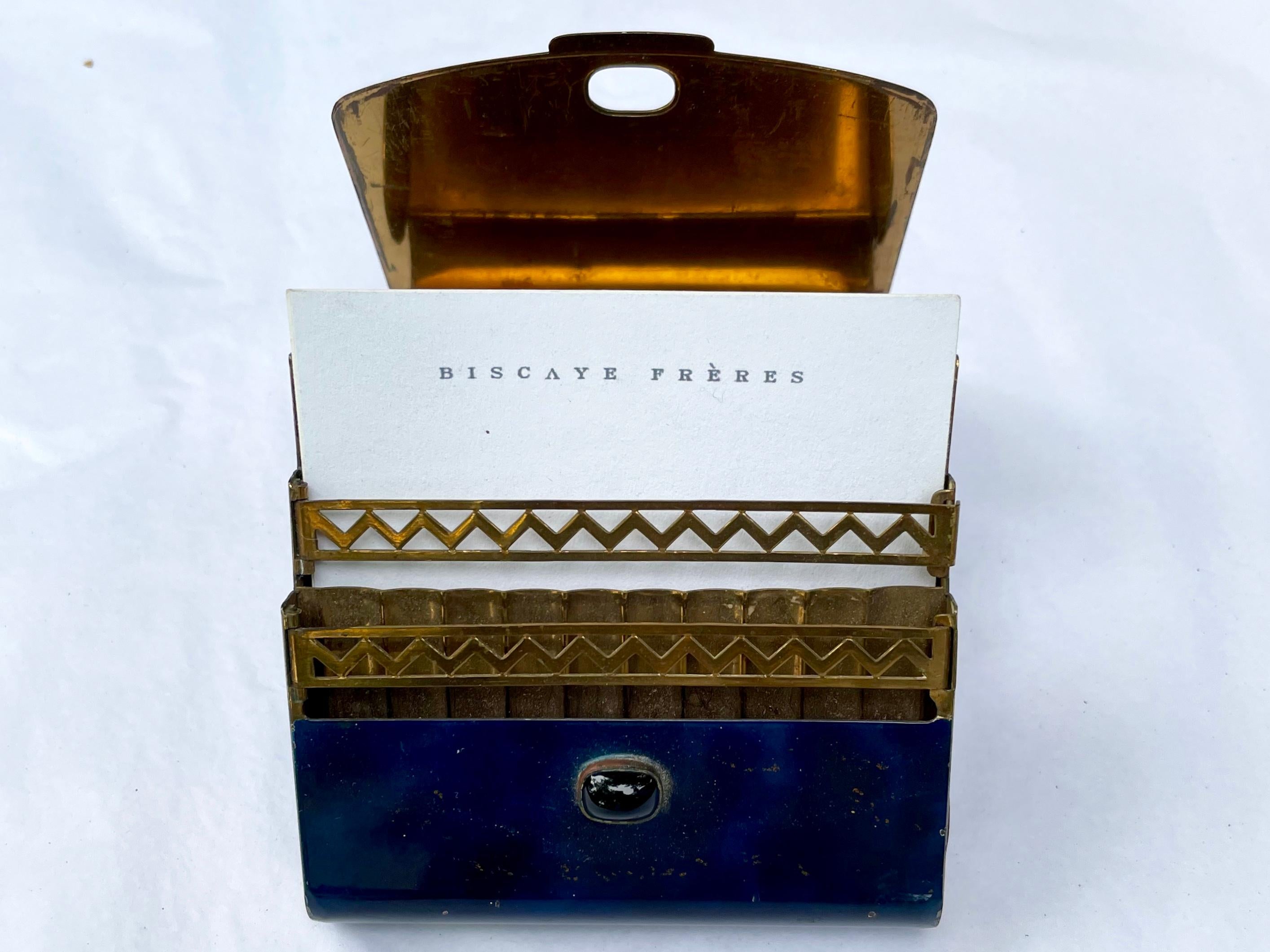 Cobalt blue and gold Forties cigarette case card holder. Vintage enameled blue metal case on gold ball feet with hinged curving lid with small hard stone clasp opening to reveal gold brass interior with pop-up American Deco pierced and ridged tray