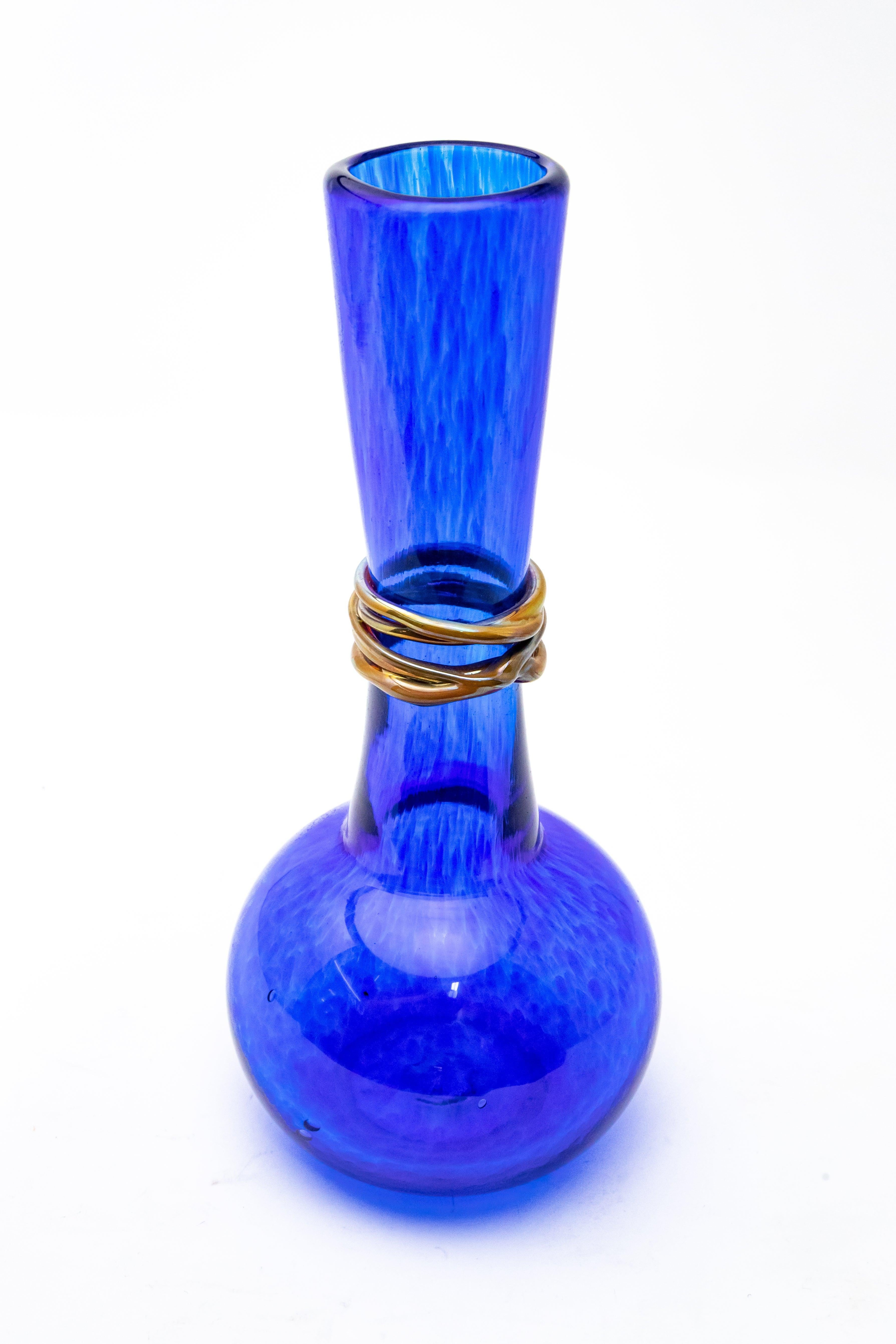 Vibrant cobalt blue forms this hand blown vase by Ingris of Chattanooga, Tennessee. An iridescent rope is twined around the neck of the piece. The vase is signed on the bottom, Ingris 04.
