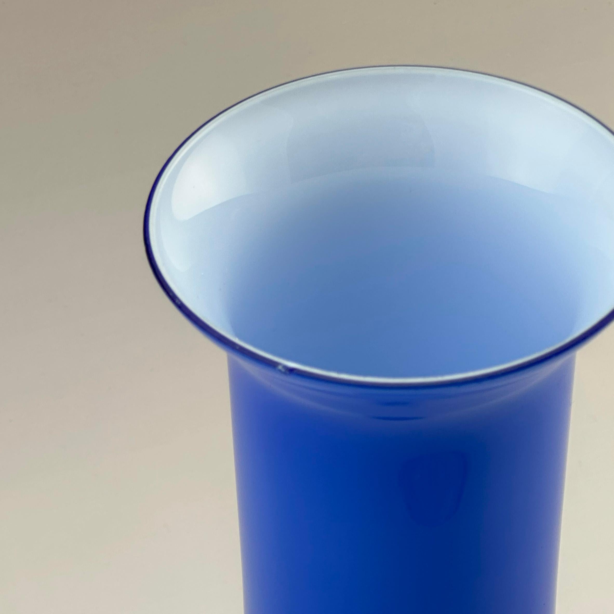 Eine leuchtend kobaltblaue Glasvase aus Empoli, Italien, hergestellt um 1970.

Die Vase aus gehärtetem Glas besteht aus einer inneren Schicht aus opakem, weißem Glas, das mit leuchtendem Kobaltblau überzogen ist, wodurch Tiefe und lebendige