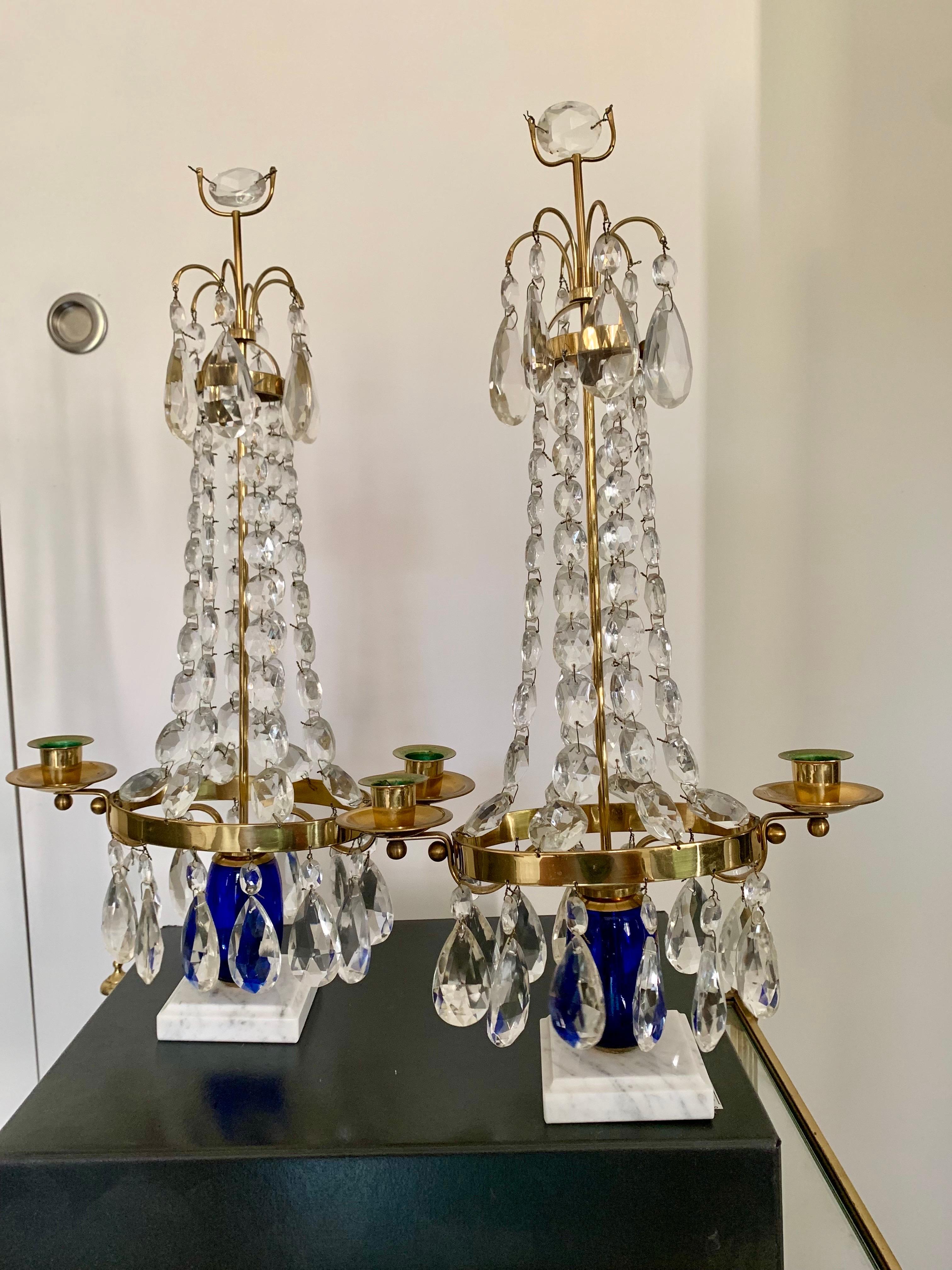 Coppia di candelabri svedesi Girandoles in vetro blu cobalto, lacrime di vetro e bronzo dorato. La base è in marmo bianco, da cui emerge una colonna in vetro blu cobalto che sostiene la balaustra in bronzo dorato dove poggiano le candele, e ha