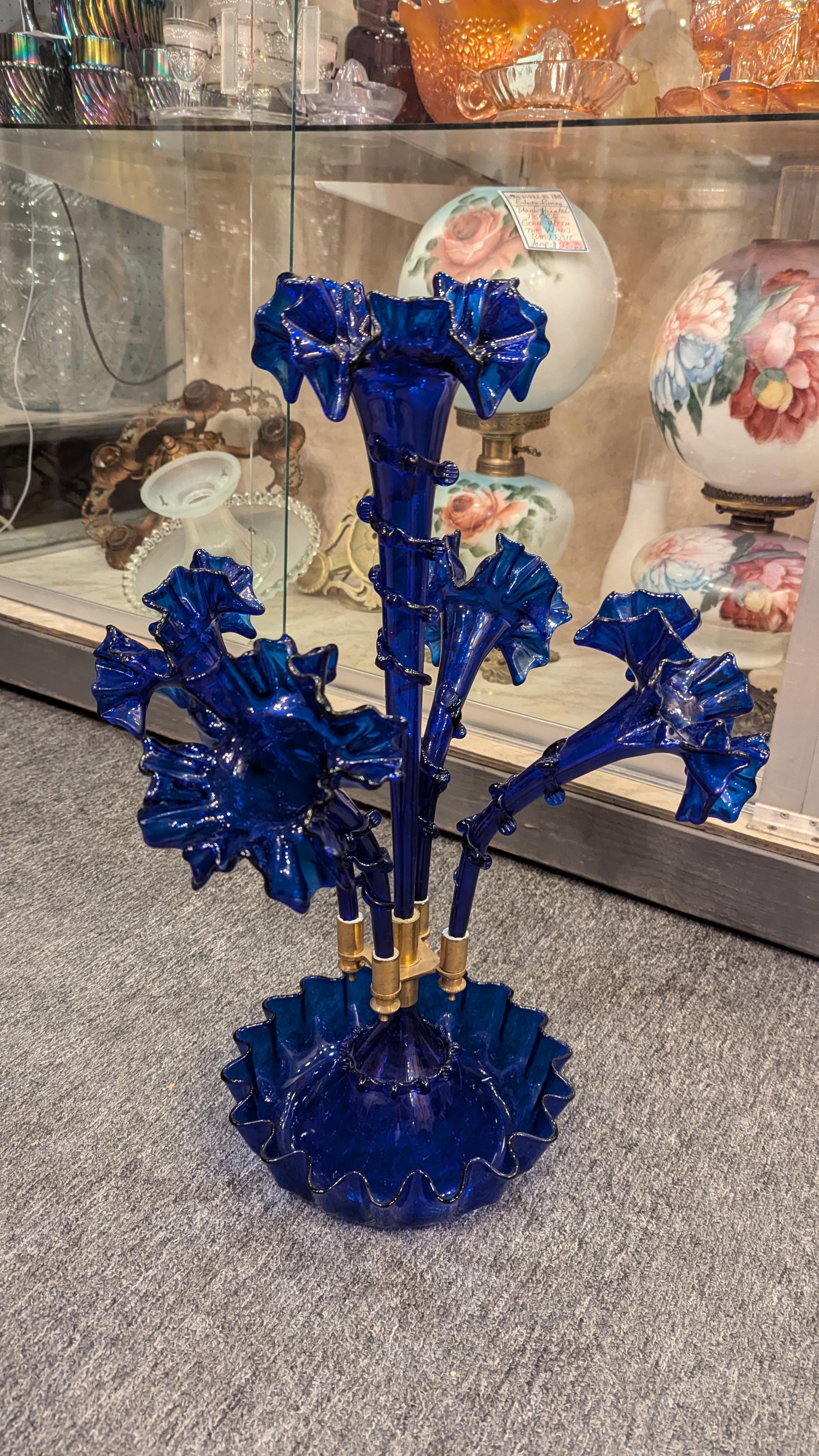 Grande epergna in vetro infiammato blu cobalto in stile vittoriano con ciotola arruffata, quattro corni laterali arruffati e grande corno centrale arruffato, attacchi in ottone. Colore assolutamente bello e nessun danno, credo si tratti di un vetro