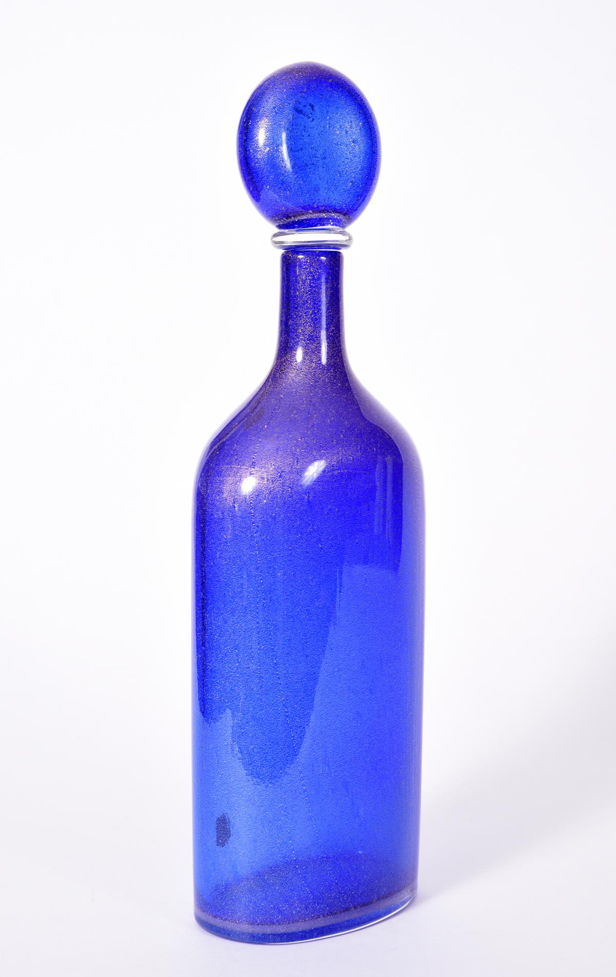 Mid-20th century cobalt blue with gold fleck Murano glass decanter. The decanter is in excellent condition, maker's mark undersigned. The decanter stand about 16.5 inches X 5.5 inches X 3 inches.