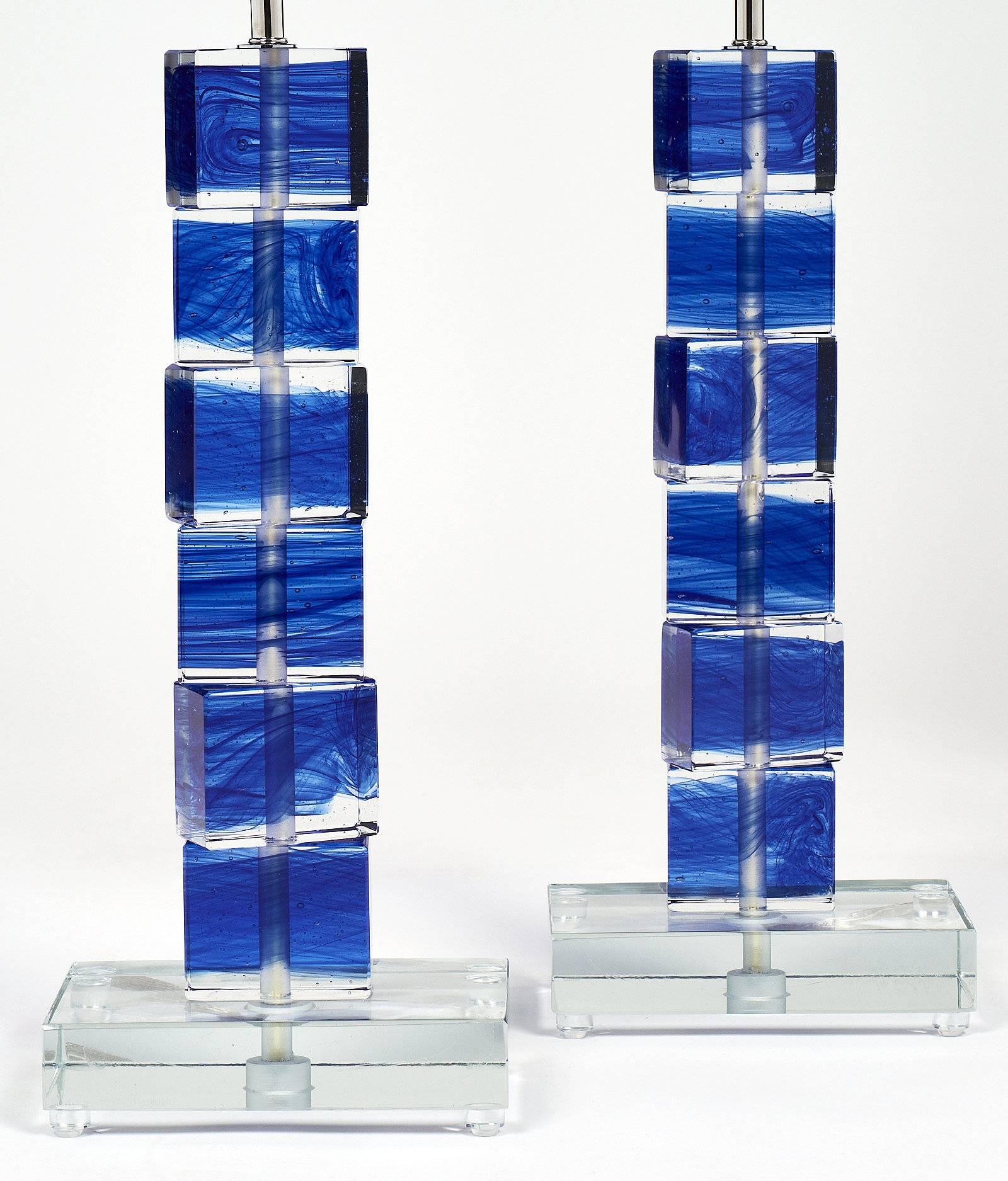 Unique pair of Murano glass cobalt blue lamps. Each features stacked clear glass cubic elements with blue color fused in the blocks. They sit on a clear glass base. These lamps have been newly wired to fit US standards.

This pair is currently