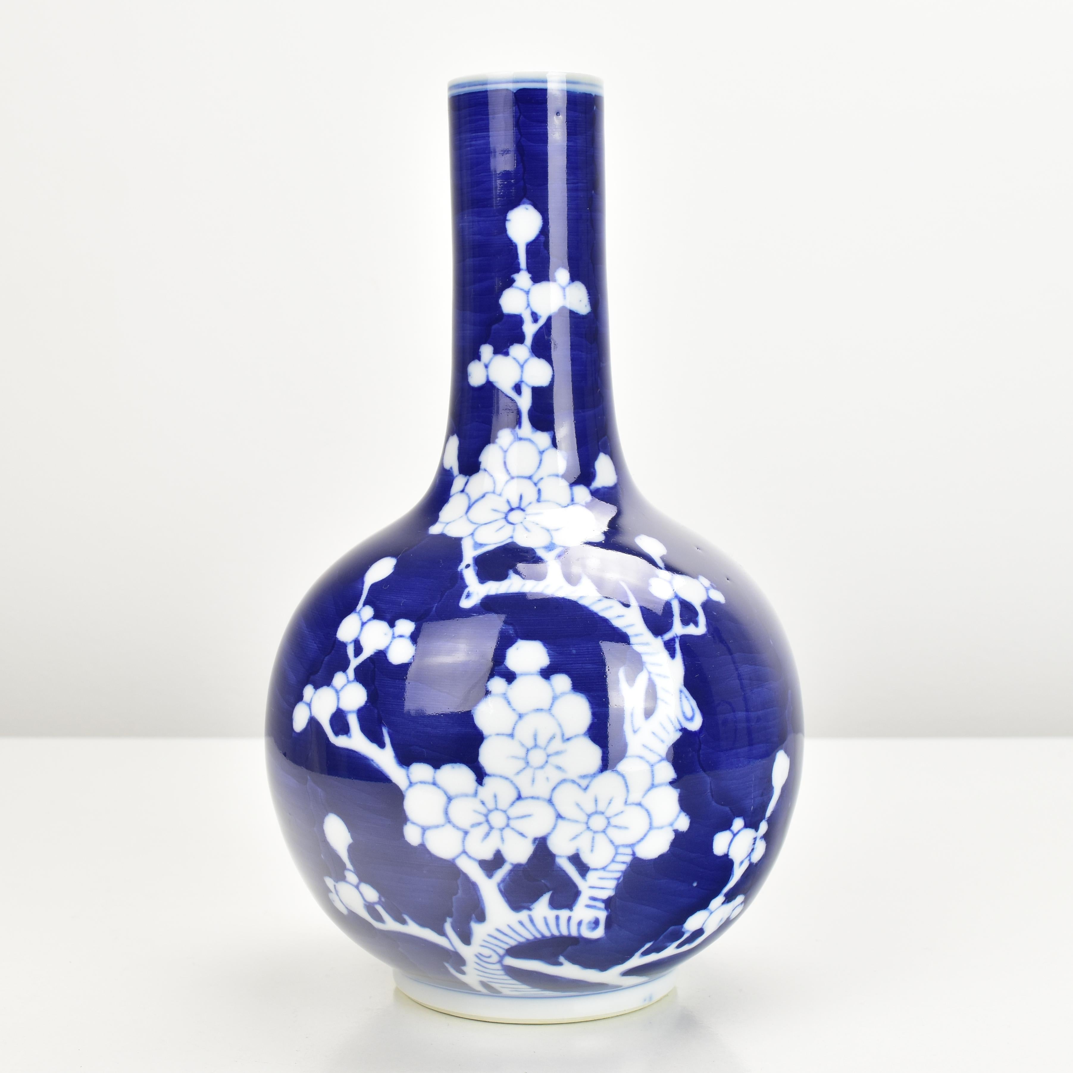 This elegant Chinese porcelain vase features a deep cobalt blue background contrasted beautifully with a delicate white prunus blossom and cracked ice pattern. 

The slender neck and rounded body enhance the traditional aesthetic, symbolizing